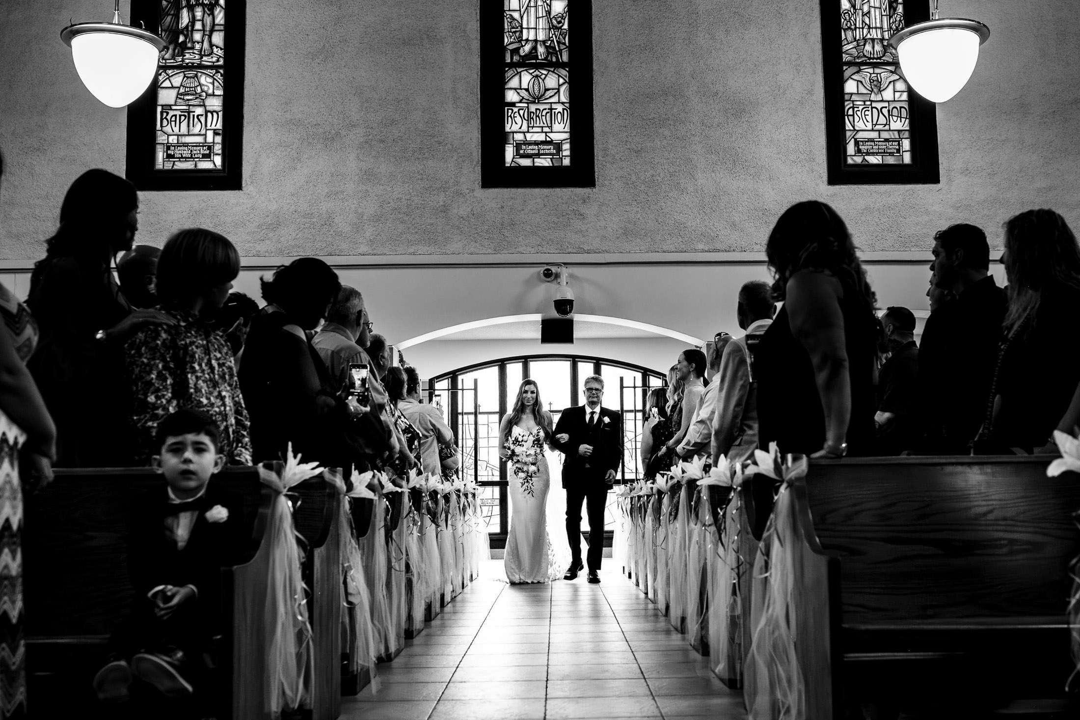 Couple walks down the aisle at an Italian wedding in Winnipeg, guests seated on both sides.