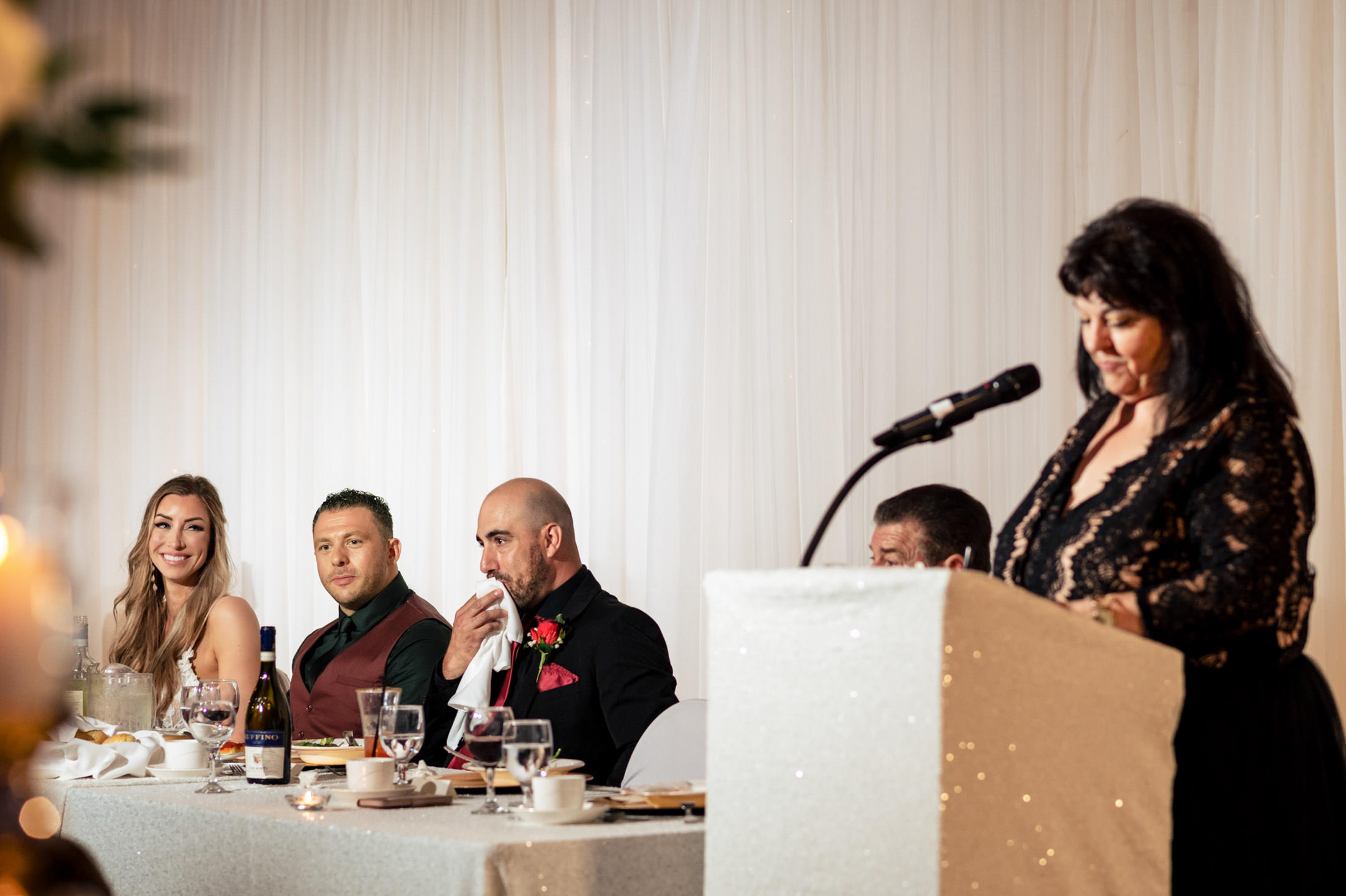 People seated at a table as a woman speaks at a podium during an Italian wedding in Winnipeg.