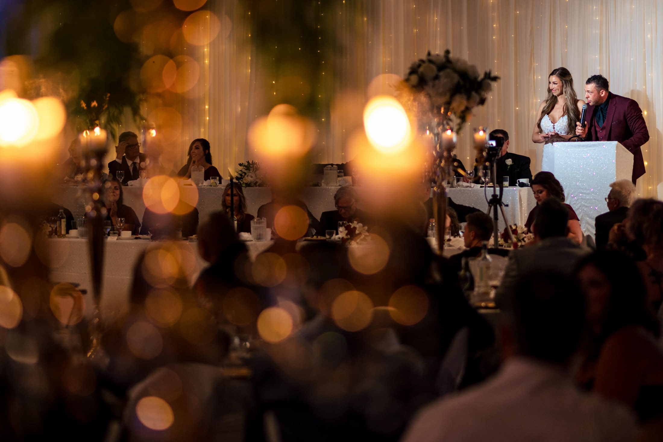 A couple at their Italian wedding reception in Winnipeg, guests seated under warm lights.