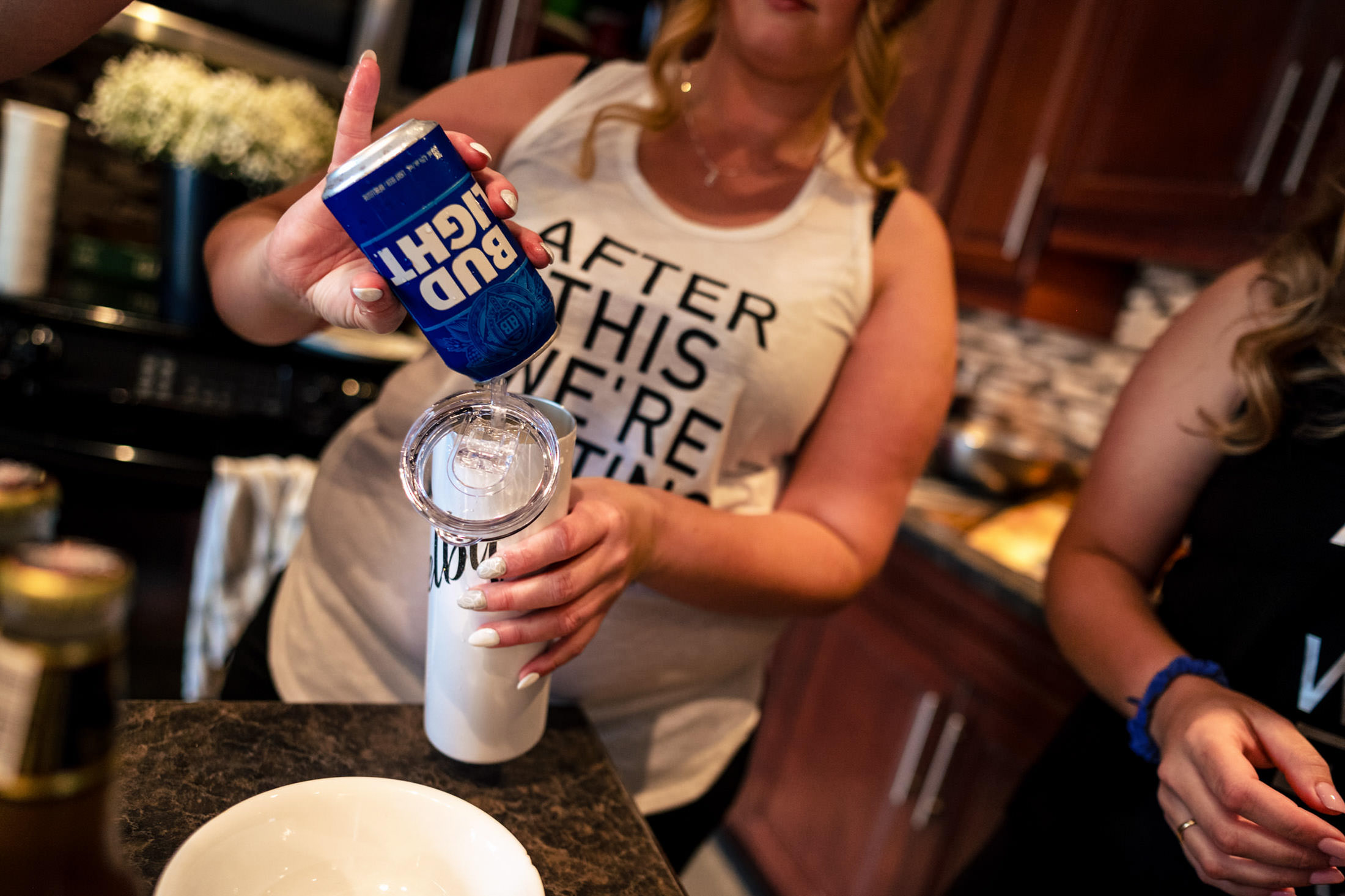 In a tank top, someone pours Bud Light in the kitchen, dreaming of a wedding at Snow Lake.