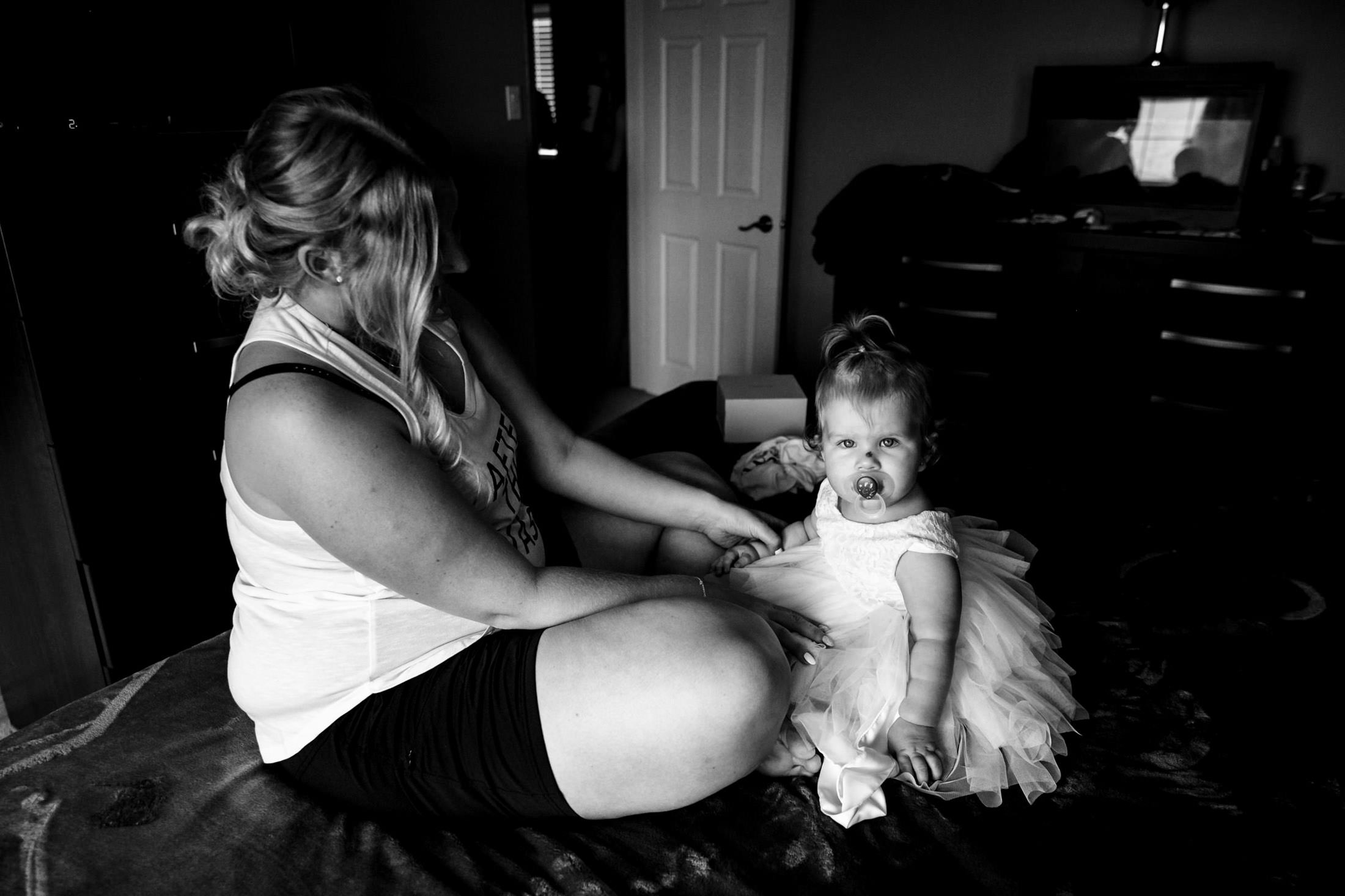 Woman and toddler in a tutu on a bed, dreaming of a wedding at Snow Lake.