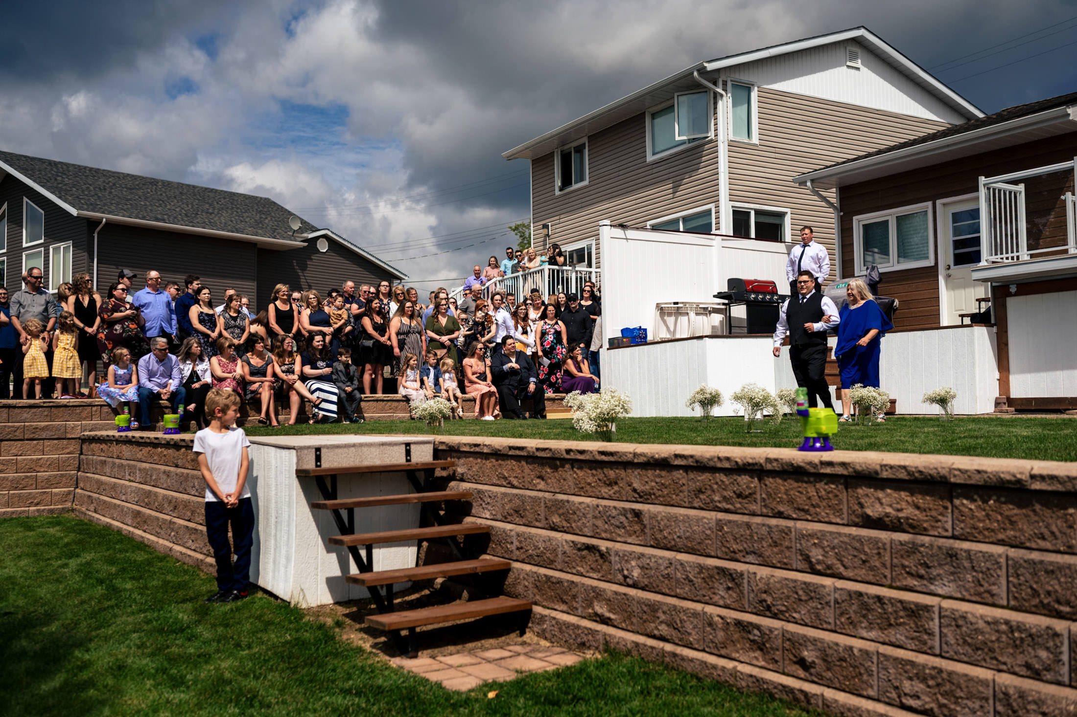 Wedding at Snow Lake with guests on a grassy lawn under a cloudy sky.