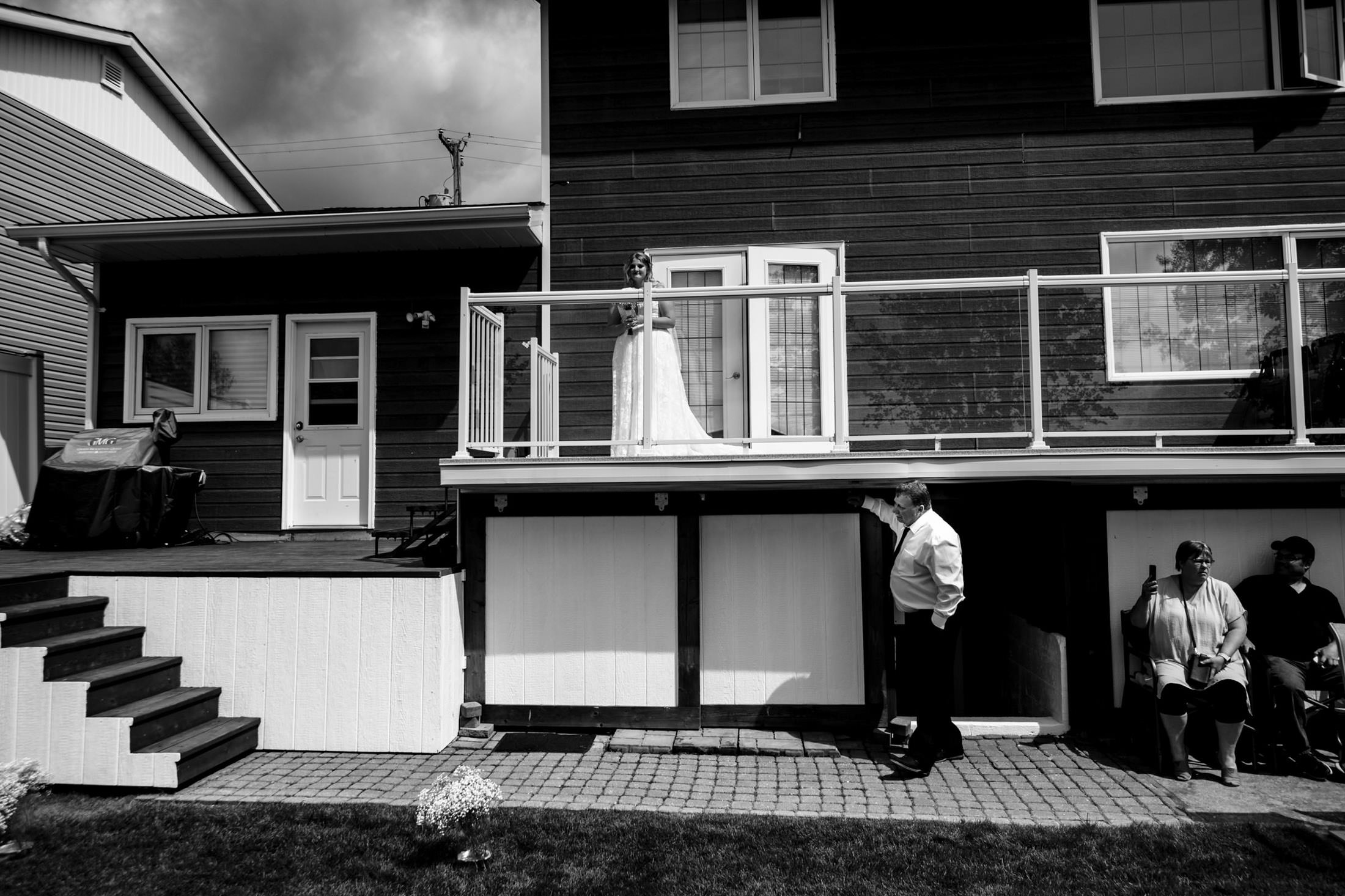 Bride on balcony, groom below; a wedding at Snow Lake in black and white by the house.