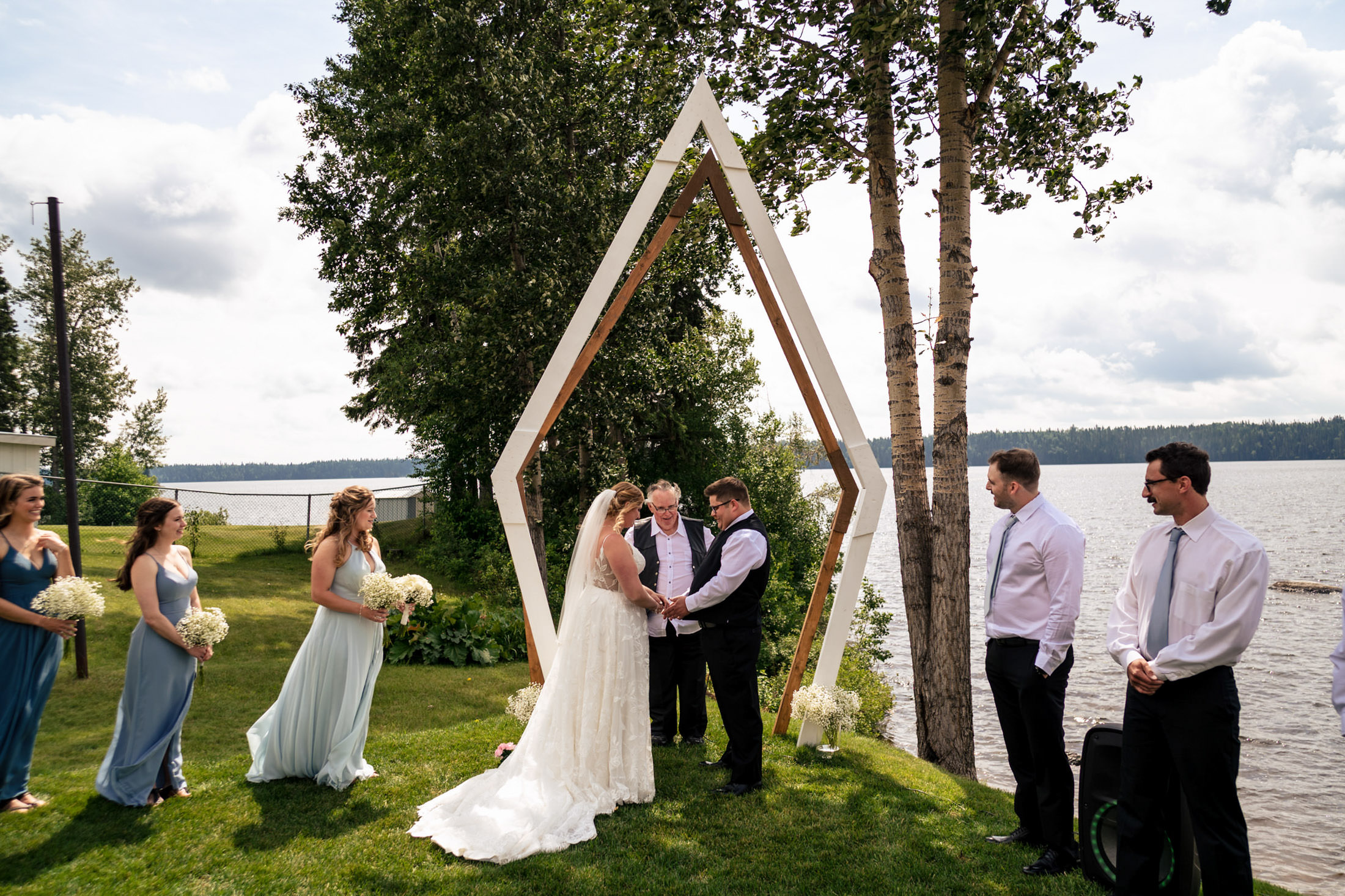 Outdoor wedding at Snow Lake, featuring a geometric arch and nearby wedding party.