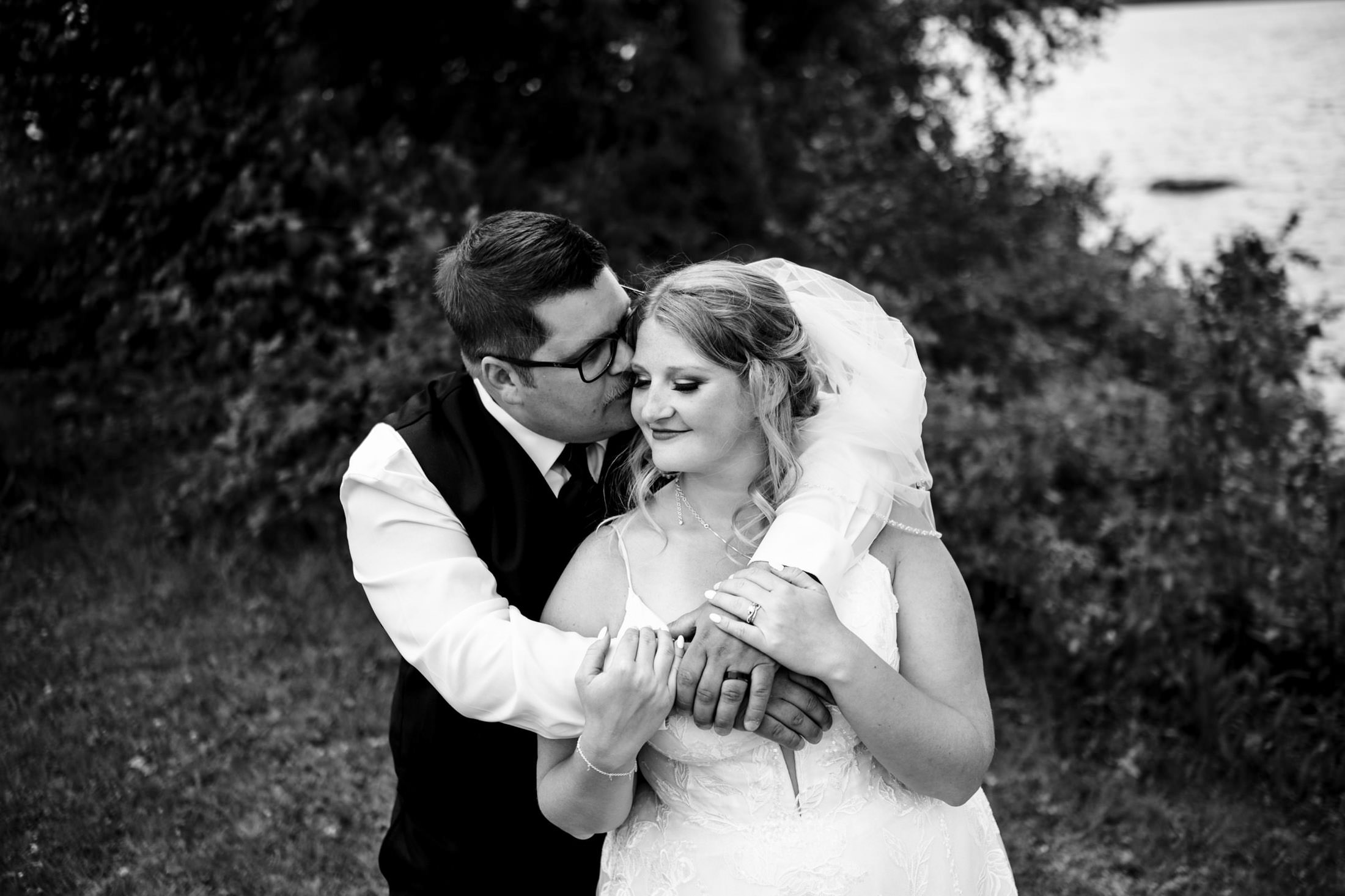 Bride and groom embracing outdoors at Snow Lake, in a classic black and white photo.