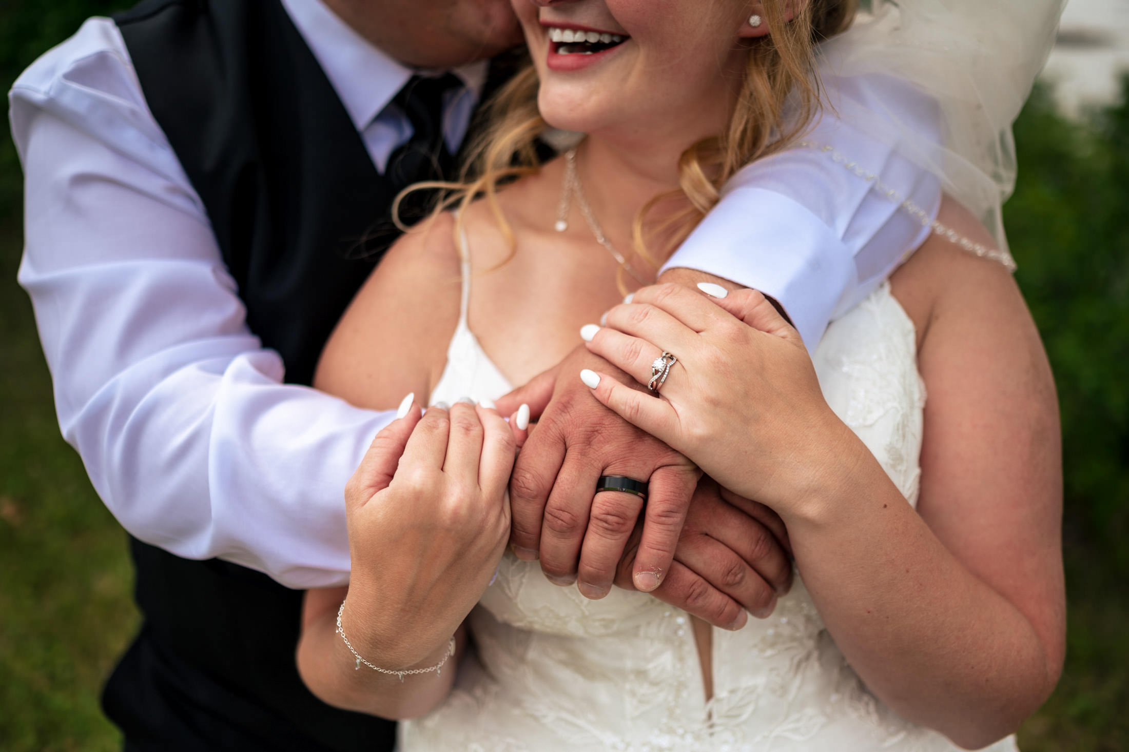 Bride and groom hugging, showing their rings and smiling at Snow Lake wedding.