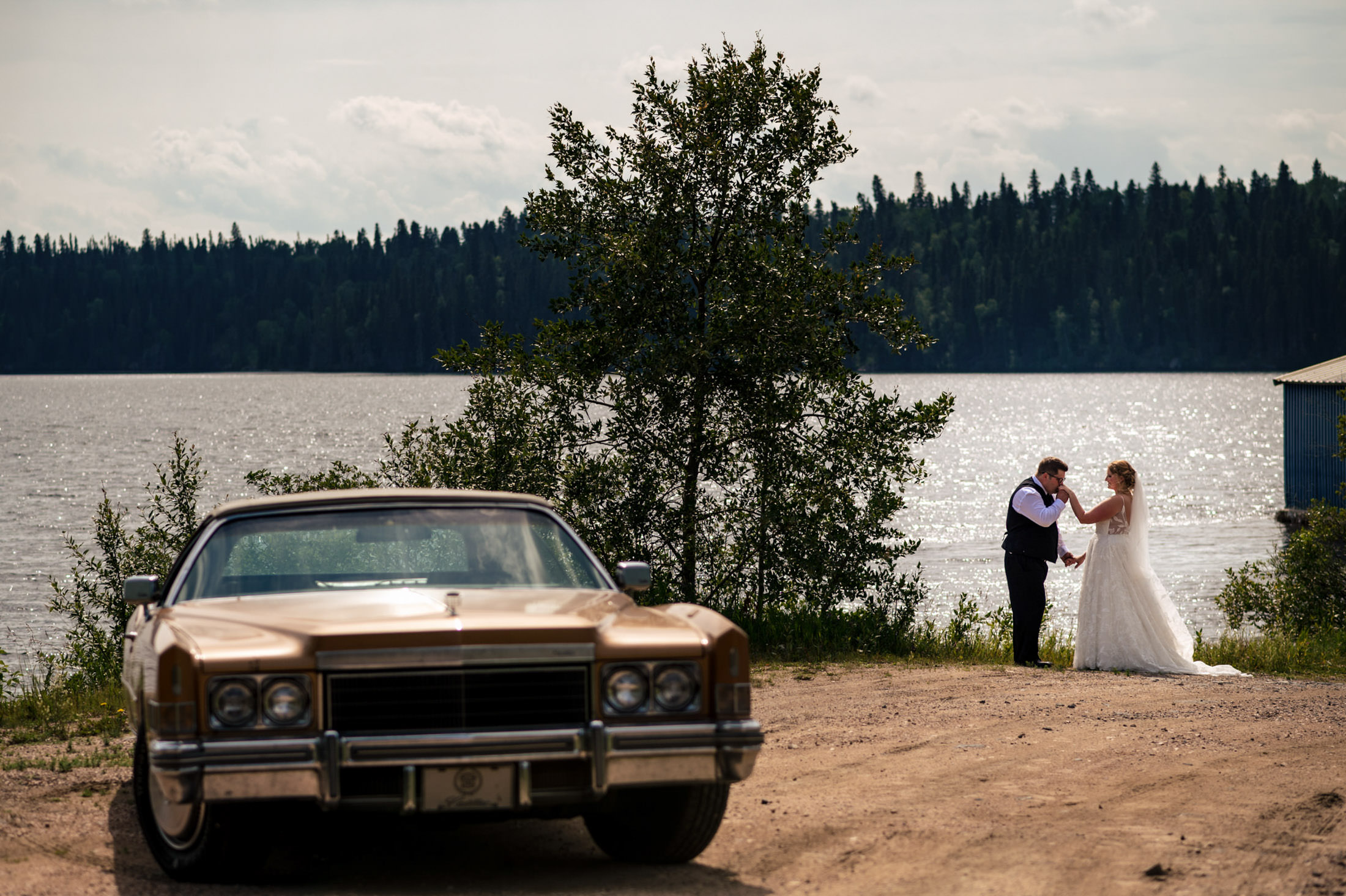 A couple dances by a vintage car at Snow Lake, with a forested backdrop.