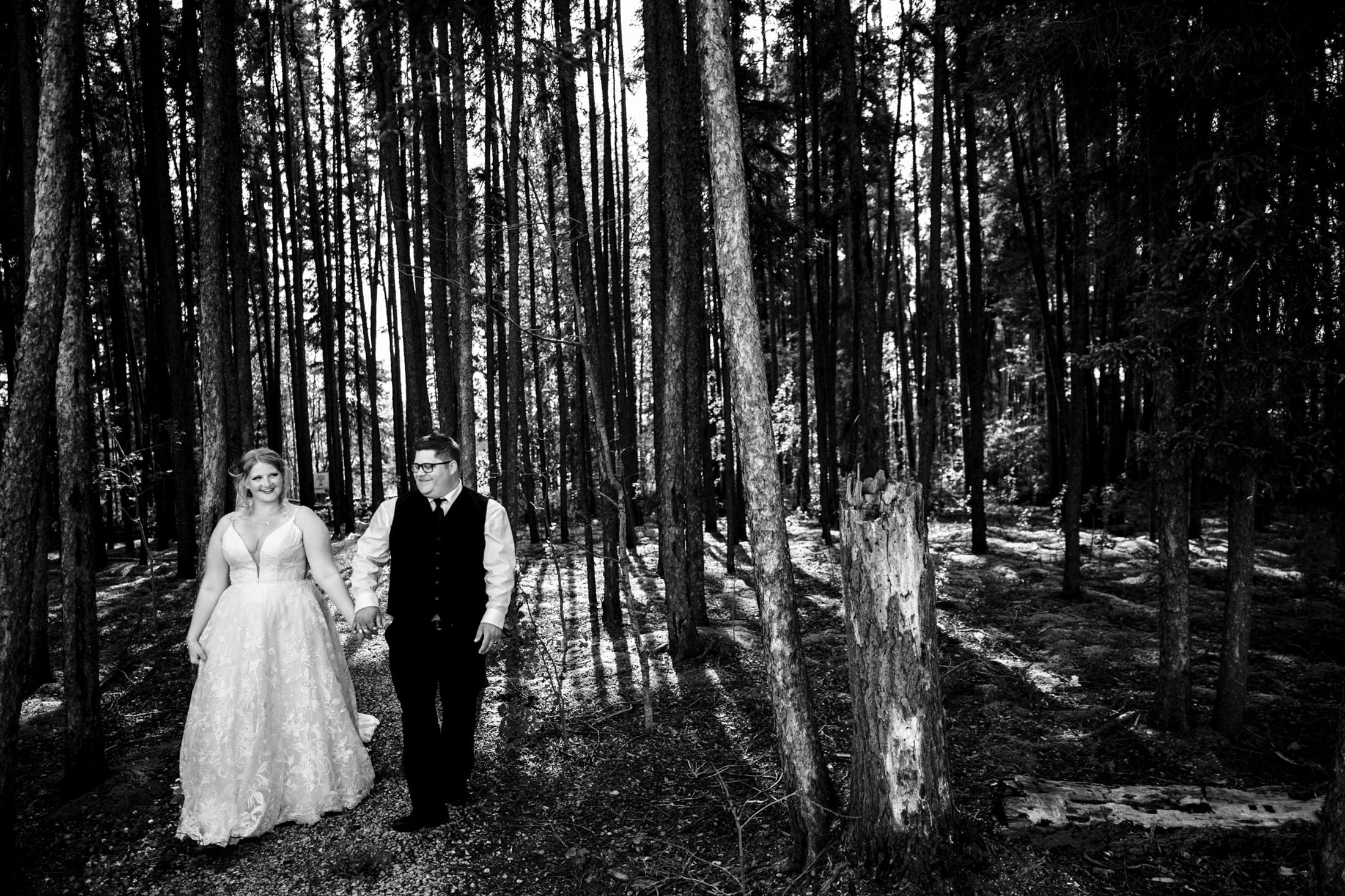 Bride and groom stroll hand in hand through Snow Lake’s sunlit forest.