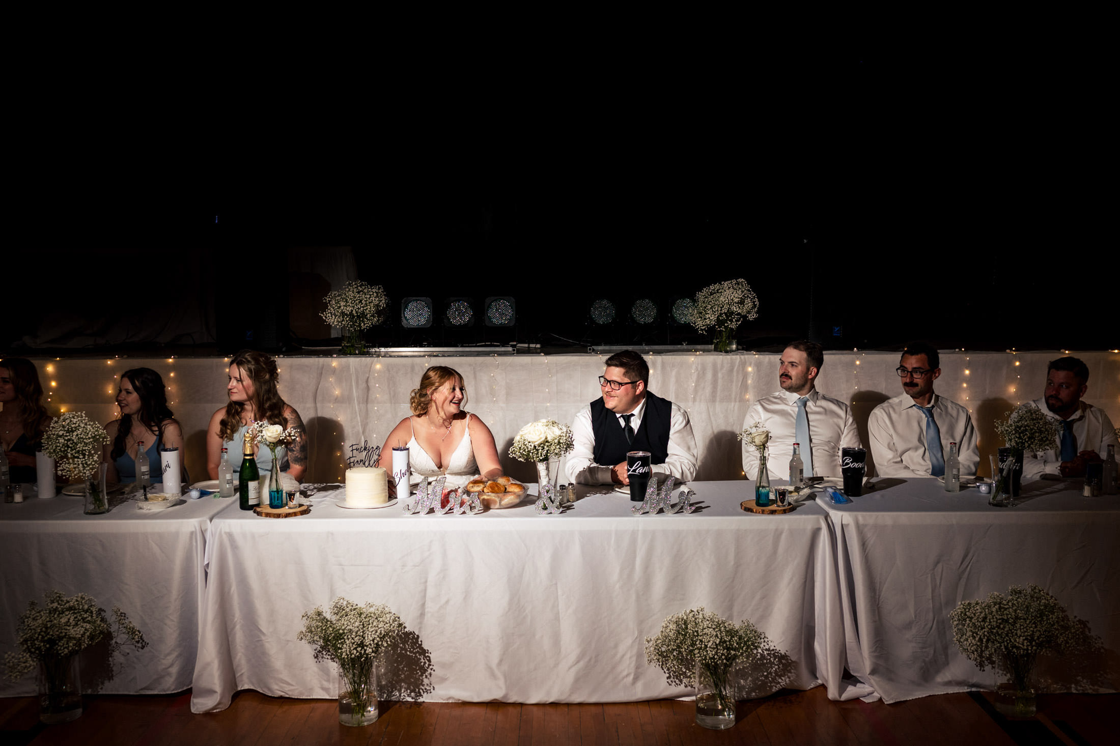 Bride and groom smiling at each other at a Snow Lake wedding table with guests.