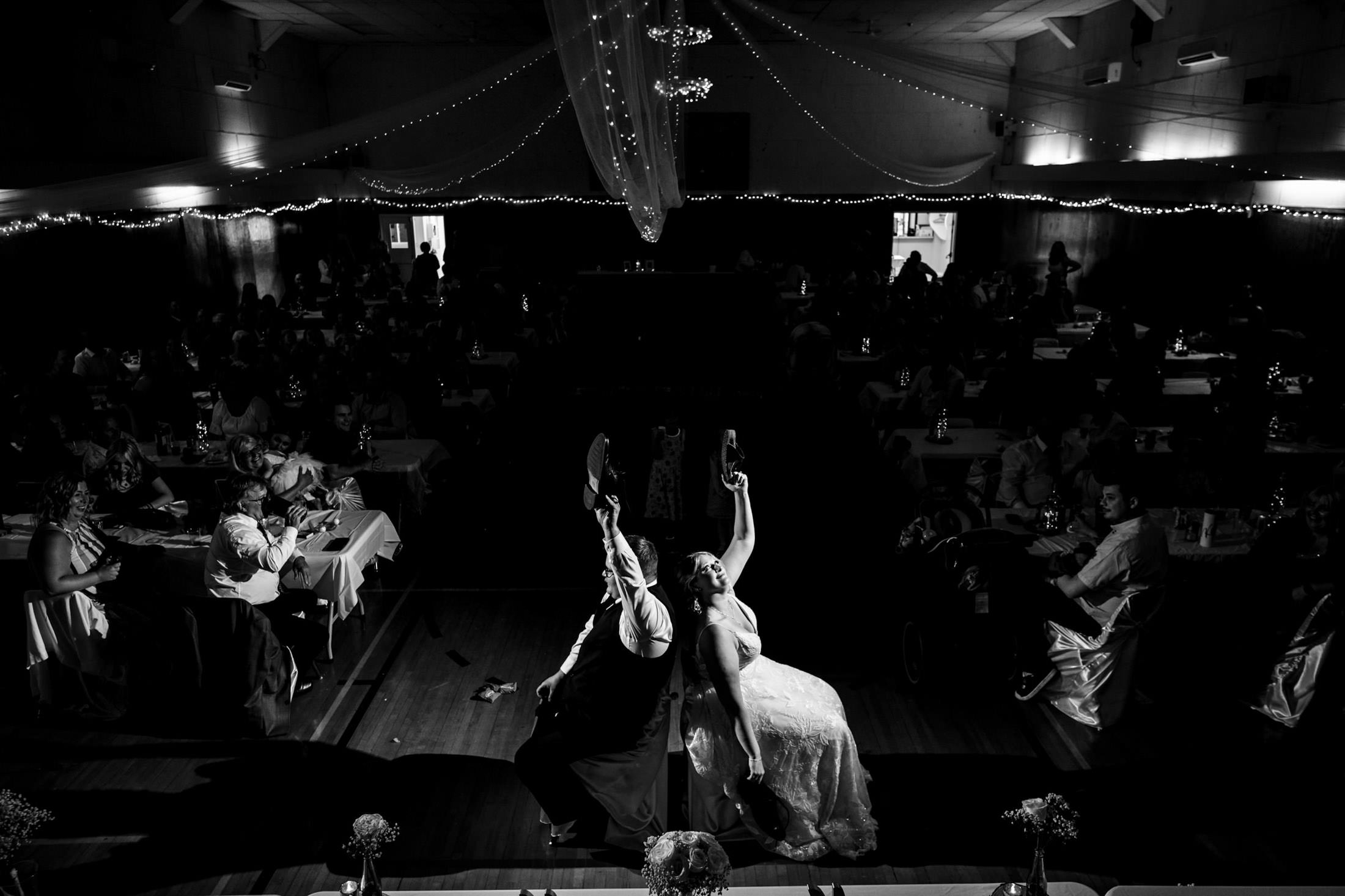A couple dancing joyfully at a Snow Lake wedding under dim hall lights.