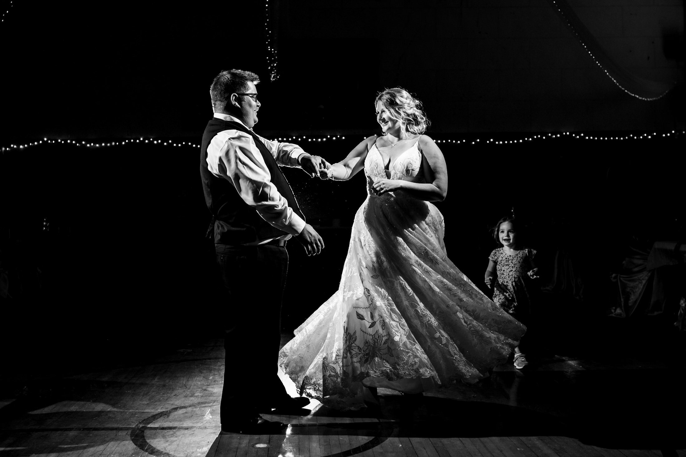 A couple dances joyfully at the Snow Lake wedding, with a child watching nearby.