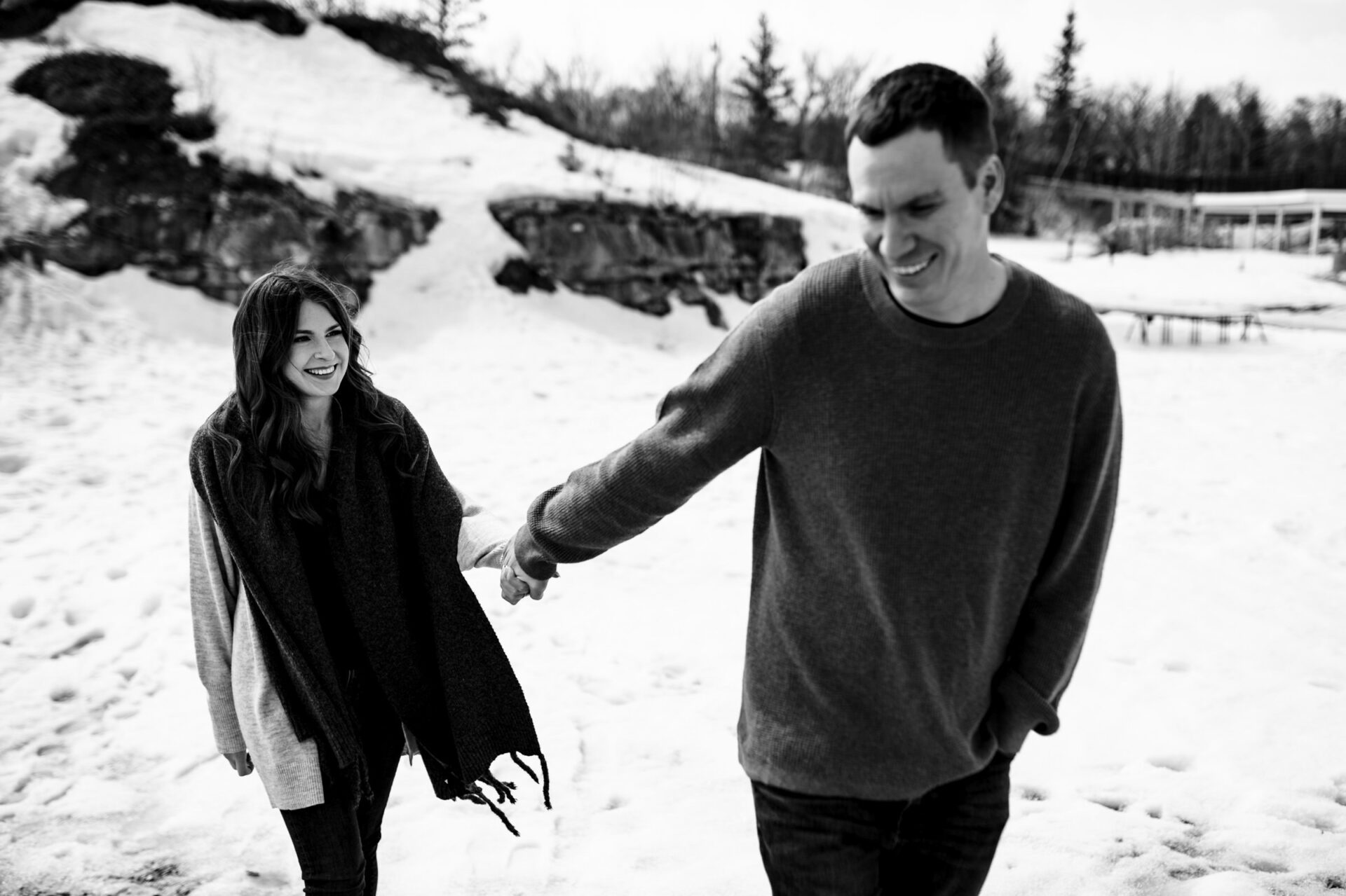 Best Winnipeg wedding photos: couple walking, holding hands and smiling on a snowy path.