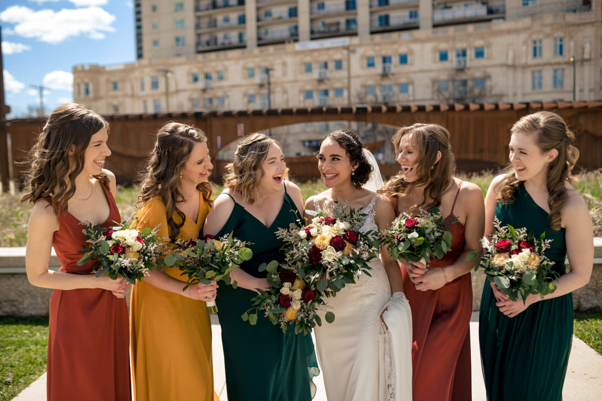 Bride laughing with bridesmaids, holding bouquets in the best Winnipeg wedding photos.