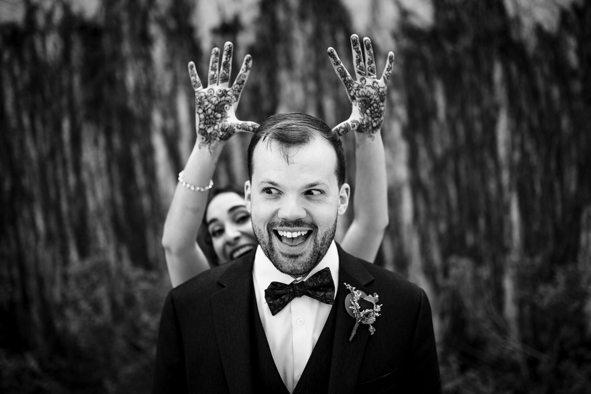 Bride playfully poses, showing hennaed hands like antlers in Winnipeg's best wedding photo.