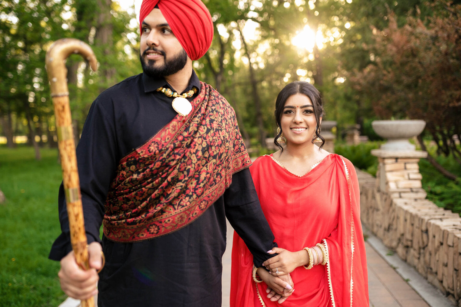Couple in traditional attire, perfect for the best Winnipeg wedding photos, strolls in the park.