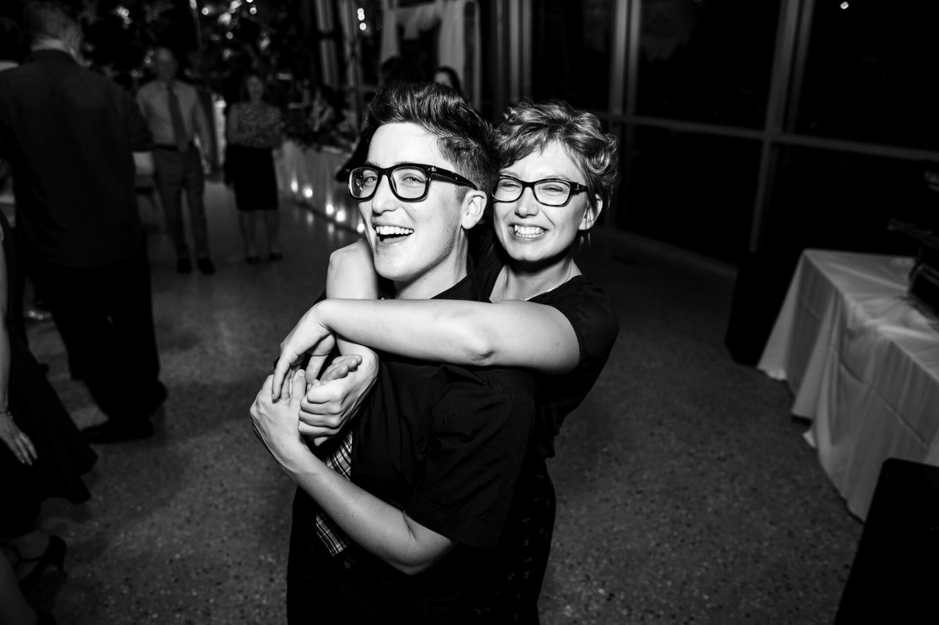 Two people hugging and smiling in a festive, dimly lit room—the best Winnipeg wedding vibe.