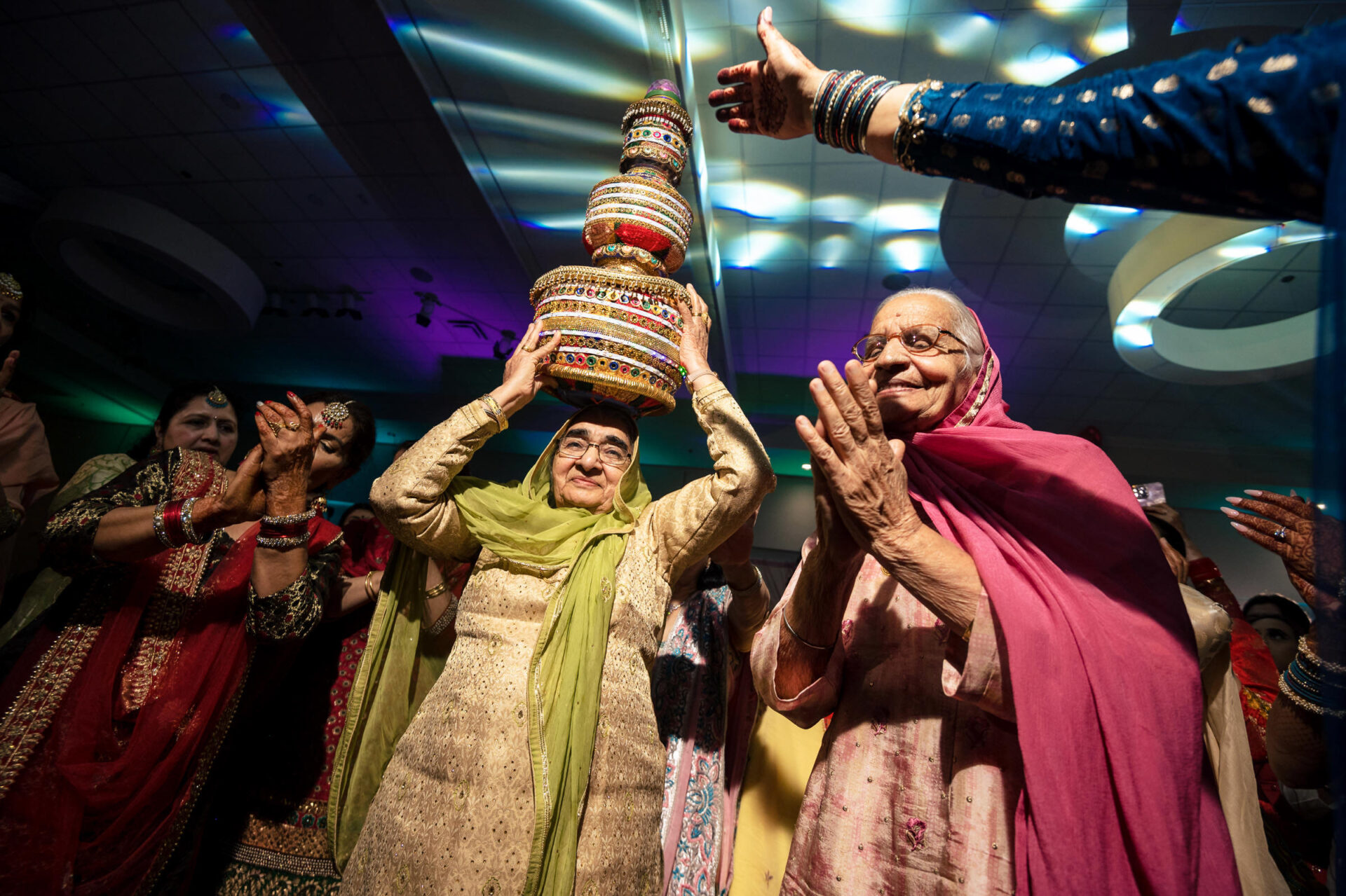 A woman balances a decorated pot, amid applause and vibrant lights, capturing the Best Winnipeg Wedding Photos.
