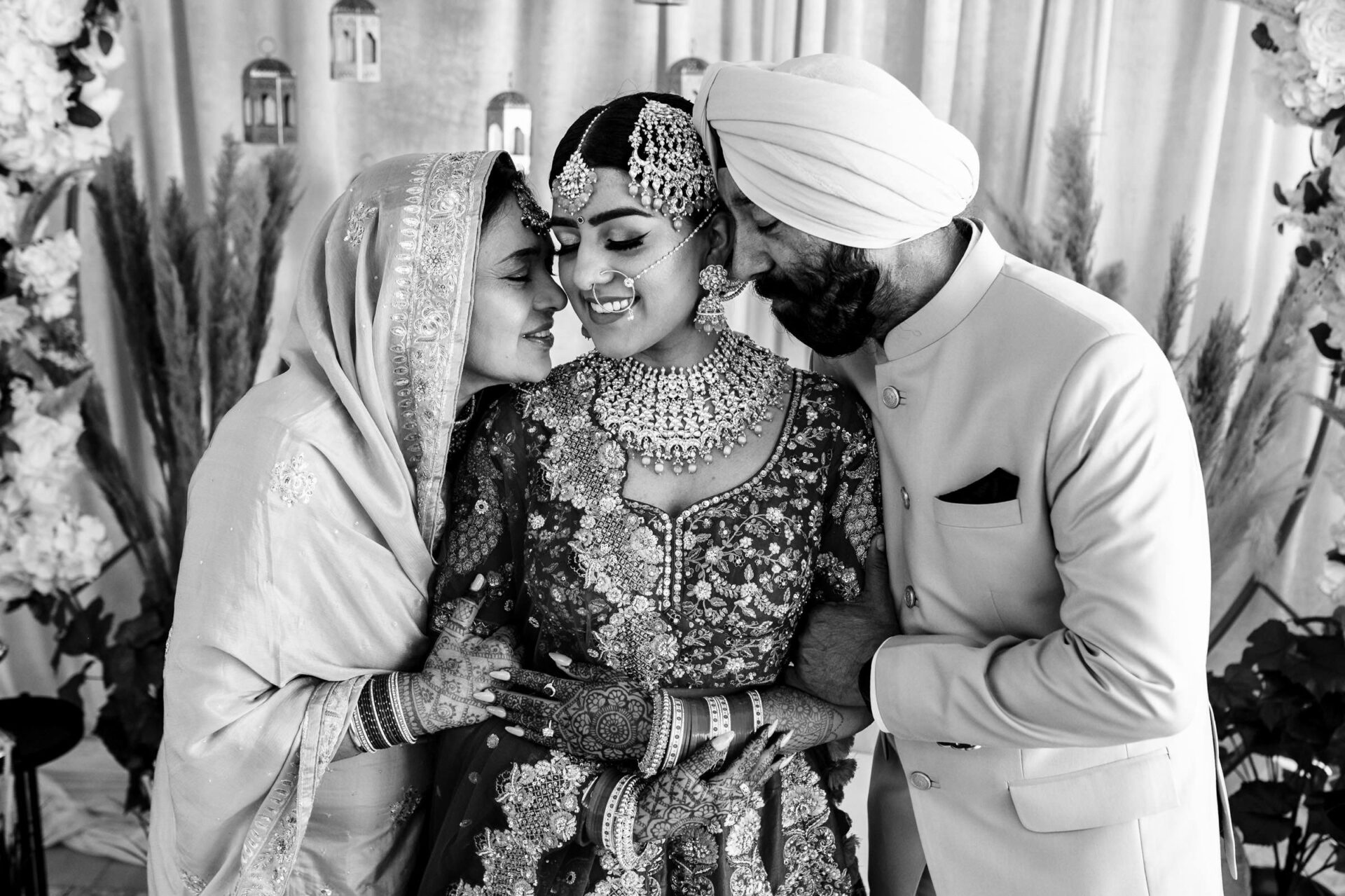 Bride with parents, in traditional attire, smiling closely. Best Winnipeg Wedding Photos. B/W.