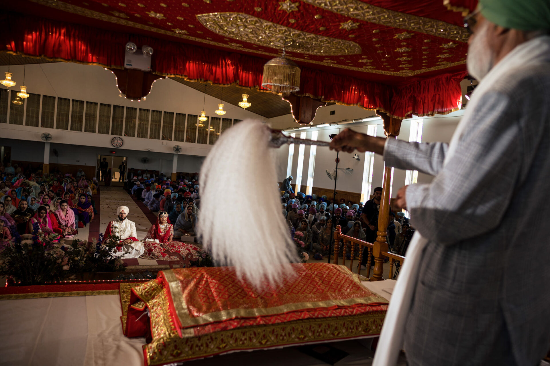 Sikh wedding in a Gurdwara, with guests seated and a chauri waving, for the best Winnipeg photos.