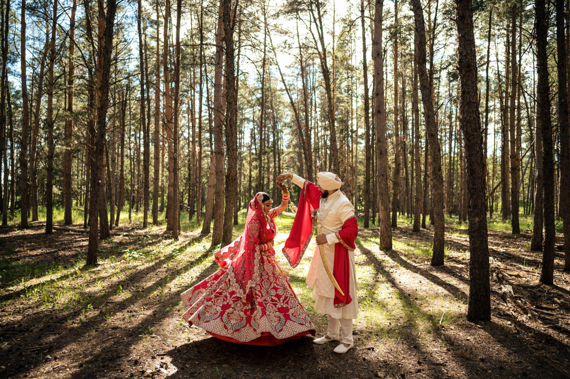 Bride and groom dance in sunlit forest, capturing the Best Winnipeg Wedding Photos.