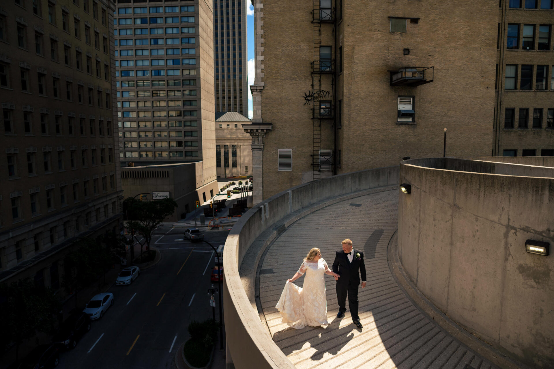 Bride and groom walk hand in hand on a sunlit path in the best Winnipeg wedding photos.