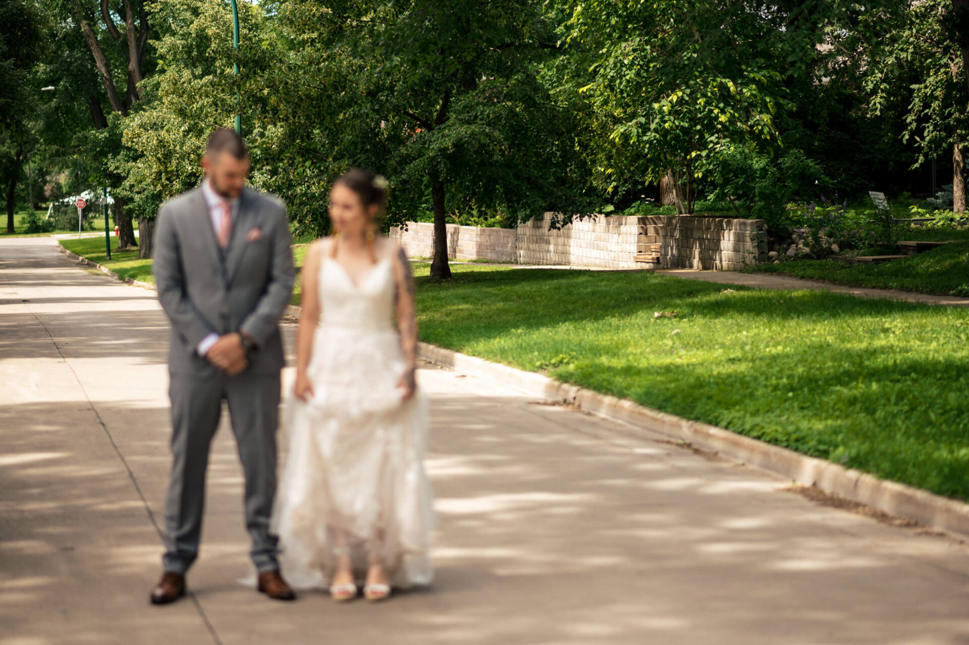 Bride and groom in Winnipeg's best sunlit pathway surrounded by trees.