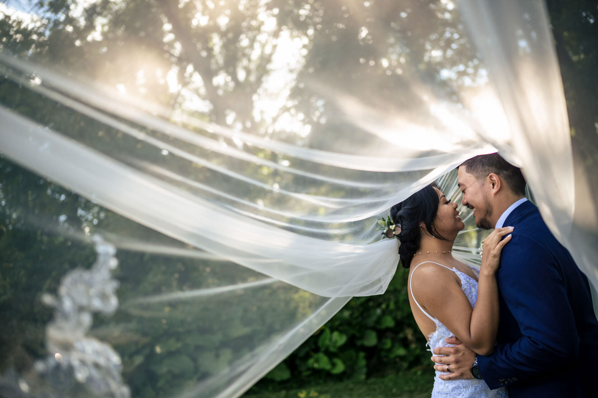 Bride and groom embracing under a veil, sunlight filtering, best Winnipeg wedding moment.