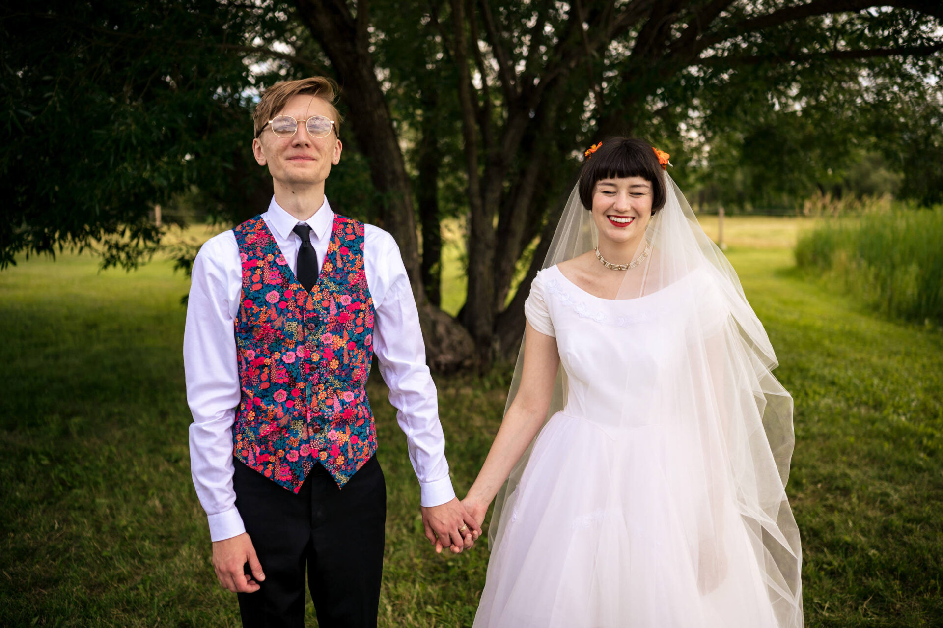 Bride and groom holding hands, smiling beneath a tree in best Winnipeg wedding photos.