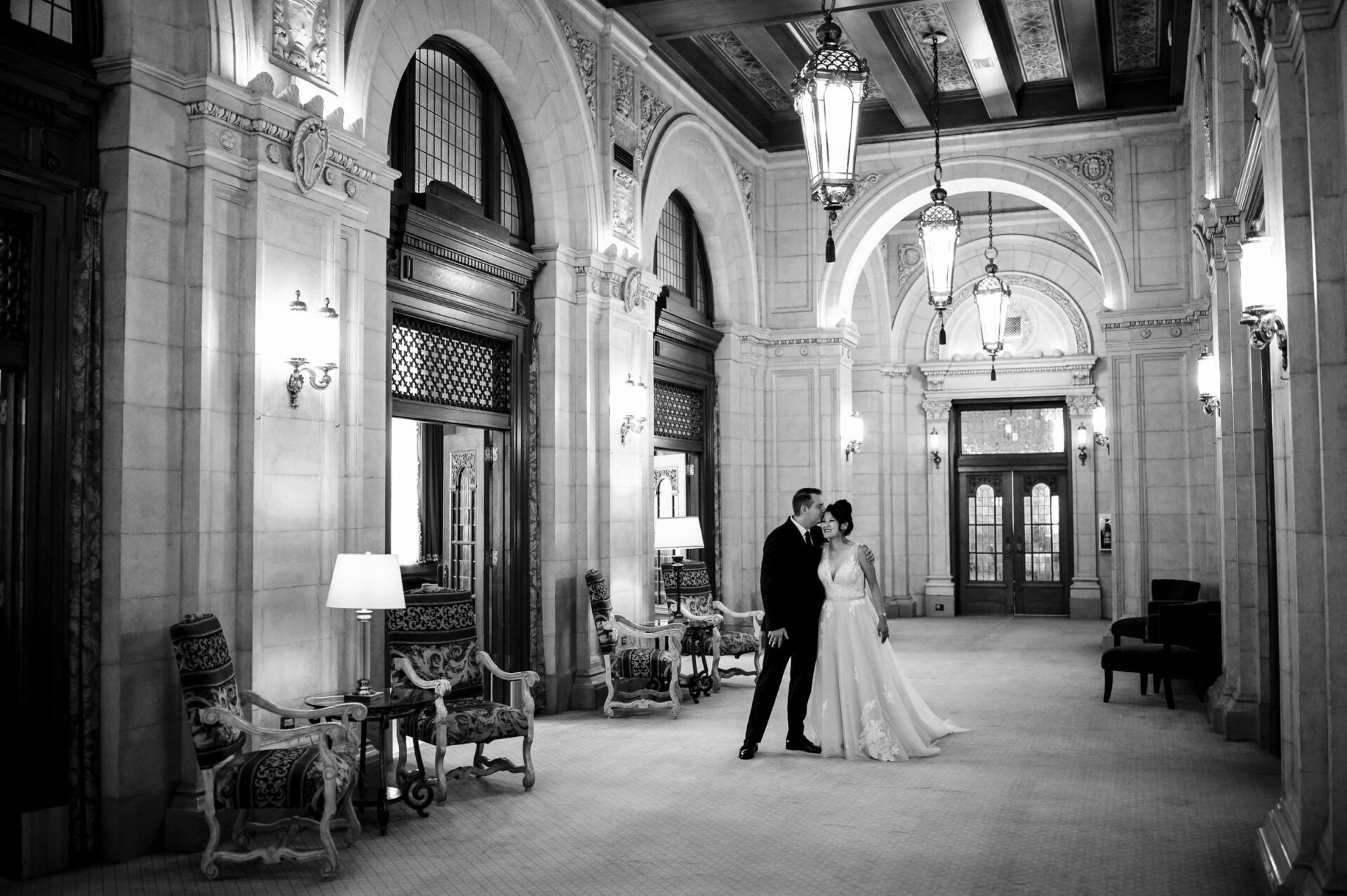 A couple in formal attire posing in Winnipeg's elegant, historic hallway.