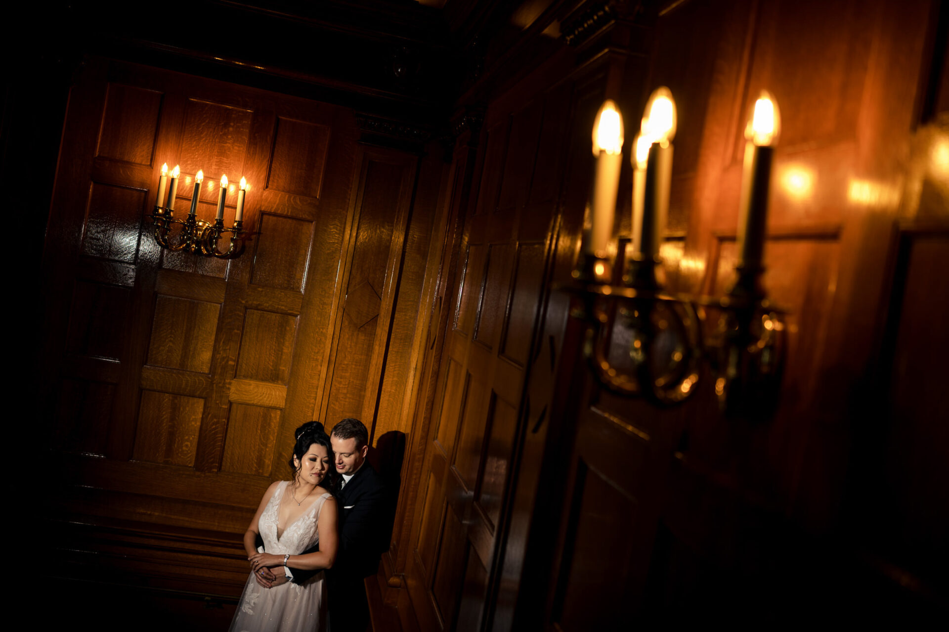 Best Winnipeg wedding photos: Couple embracing in dimly lit, elegant wood-paneled room.