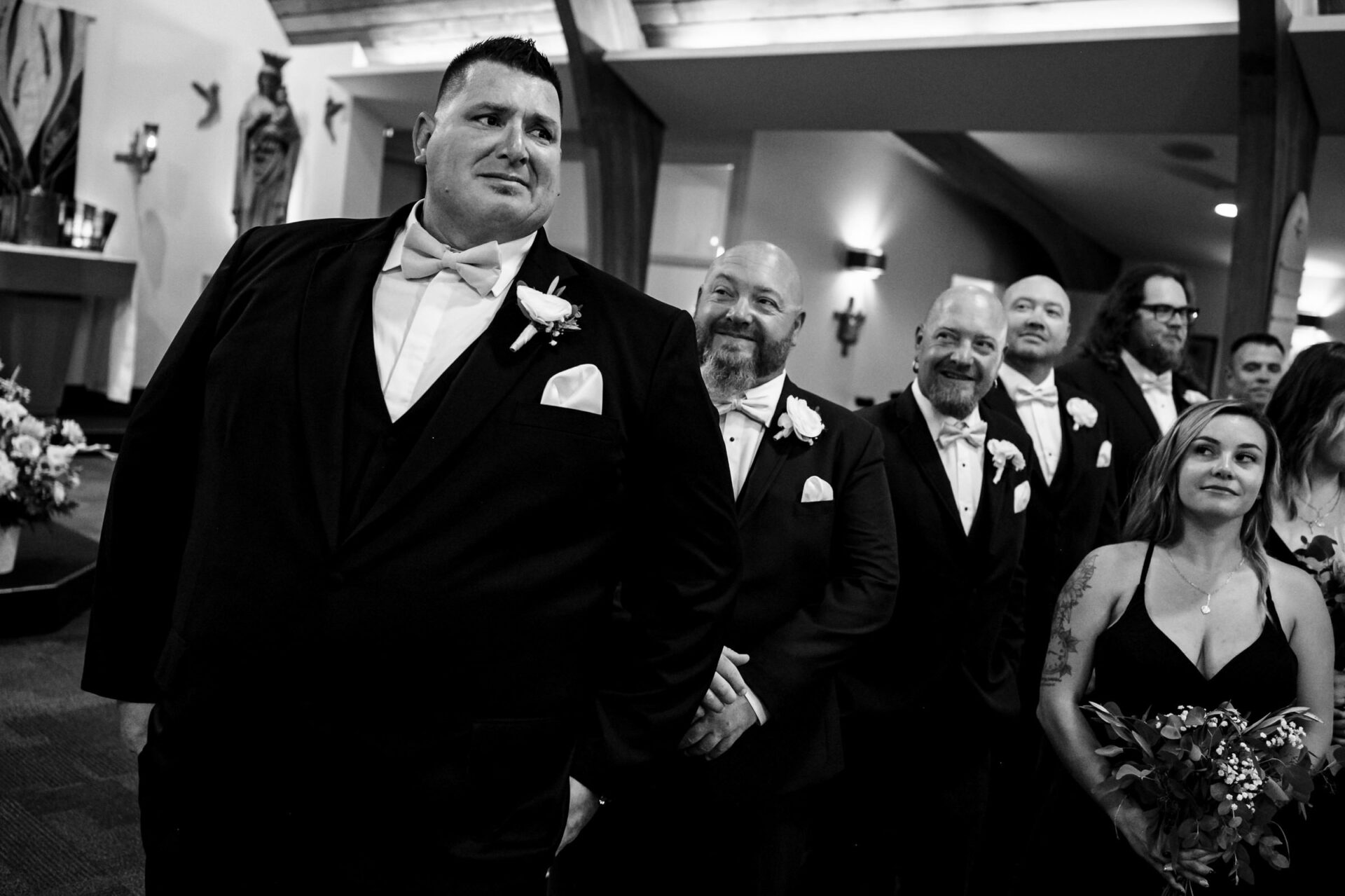 Groomsmen smile, lined up in formal suits for the best Winnipeg wedding photos.