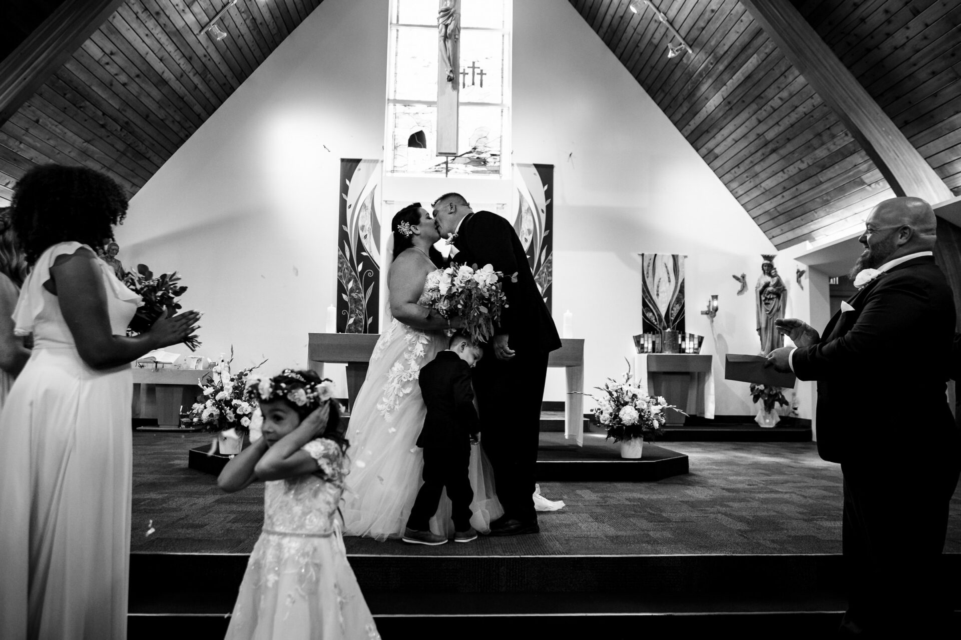 Couple kisses at altar with children during the best Winnipeg wedding photos.