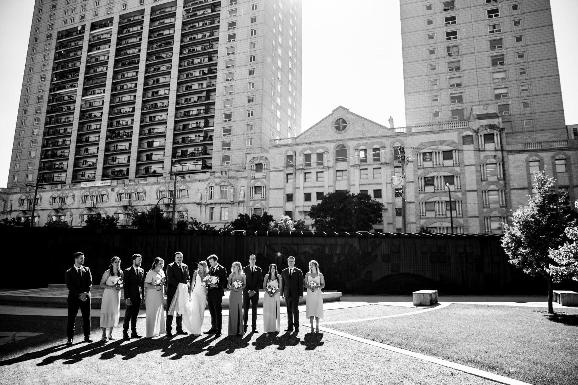 A wedding party poses for the best Winnipeg wedding photos in front of city skyscrapers.