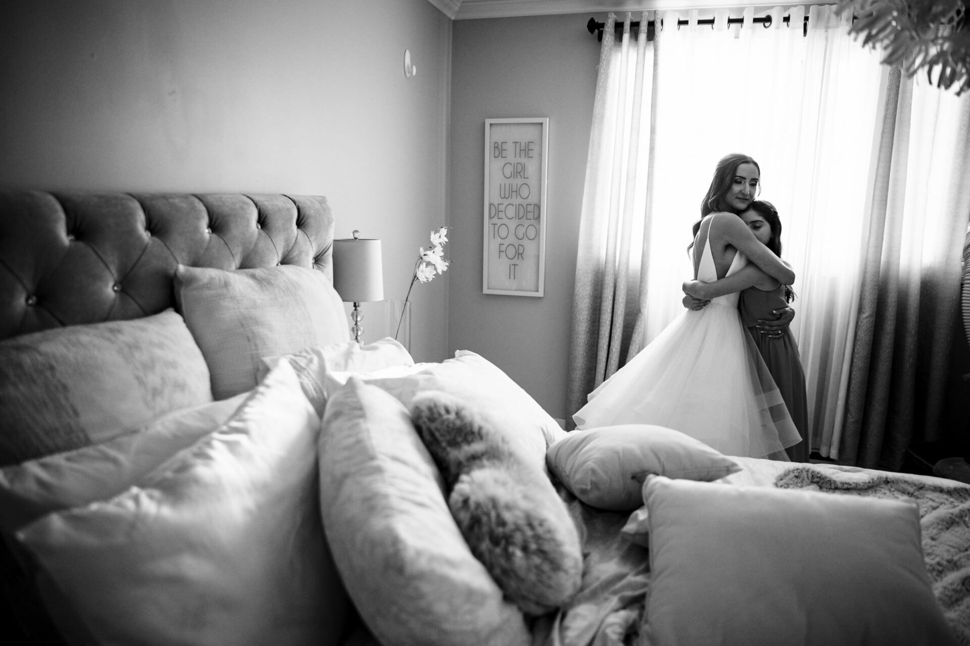 Bride and woman hugging in a sunlit room, capturing the best Winnipeg wedding photos.