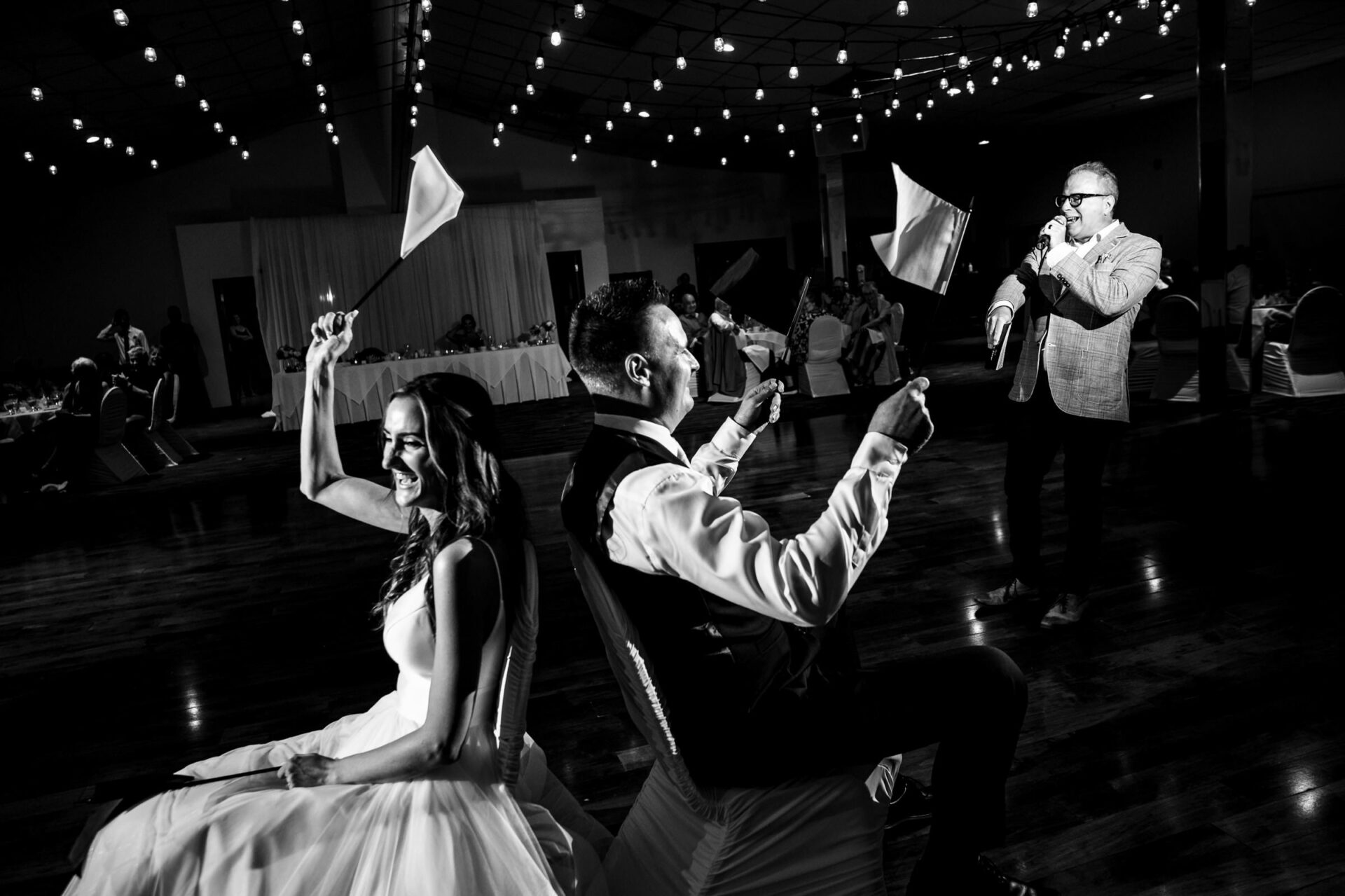Bride and groom back-to-back with flags, a man sings; best Winnipeg wedding photos.
