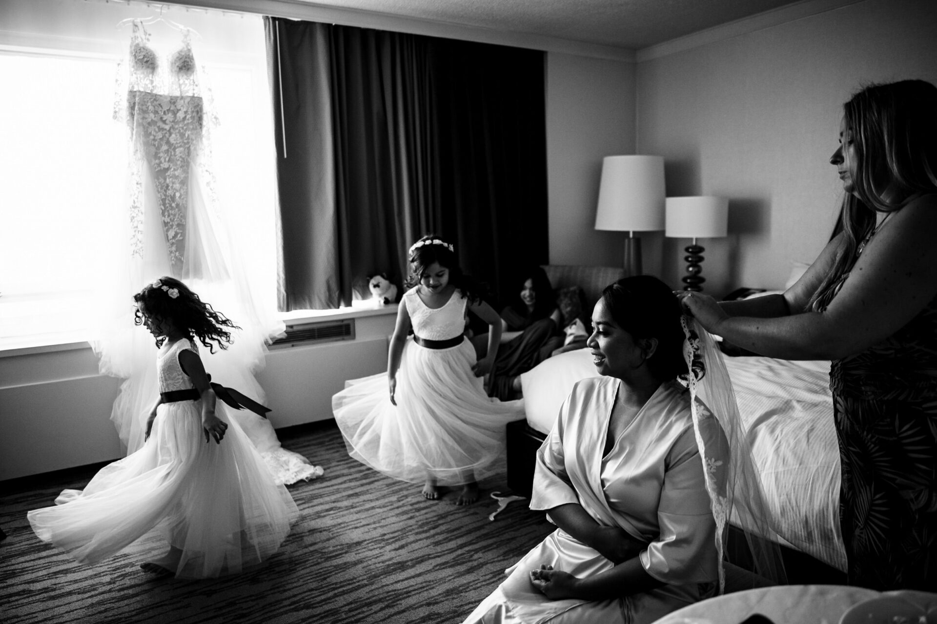 Women and girls prep in a room, creating the best Winnipeg wedding photos by a window.