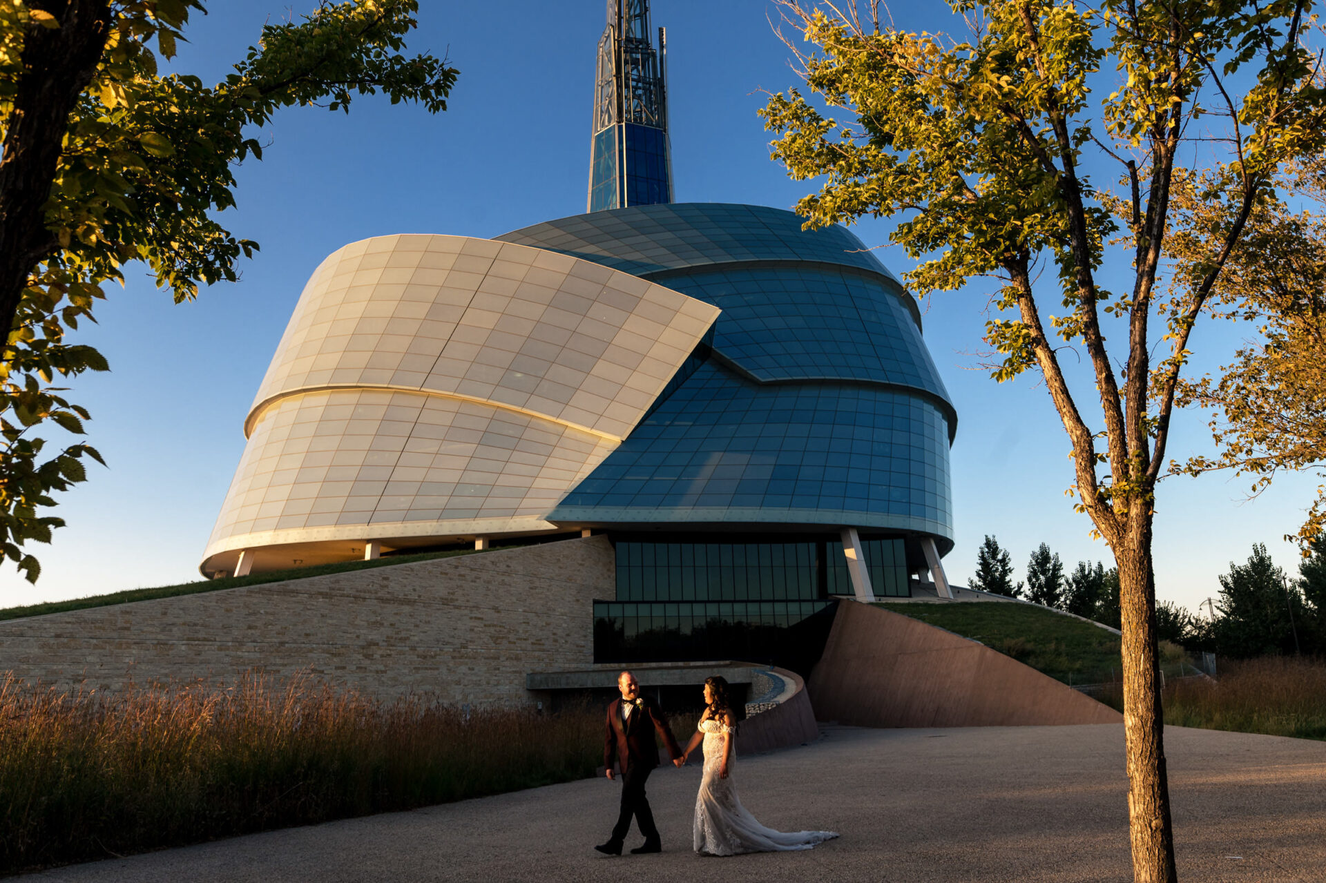 Couple walking near modern curved building, perfect for best Winnipeg wedding photos.
