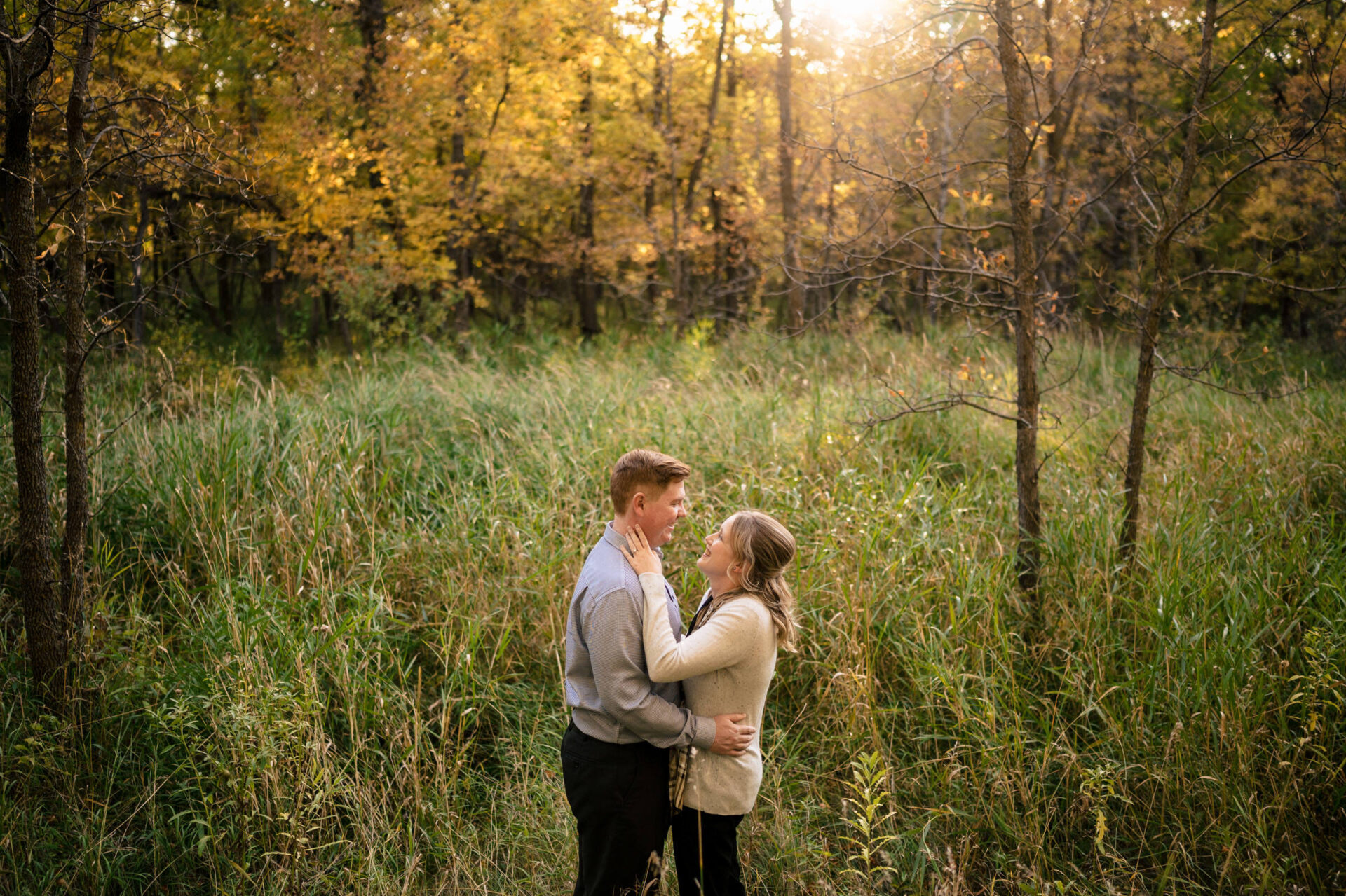 Best Winnipeg wedding photos of a couple embracing in a sunlit, autumn forest clearing.