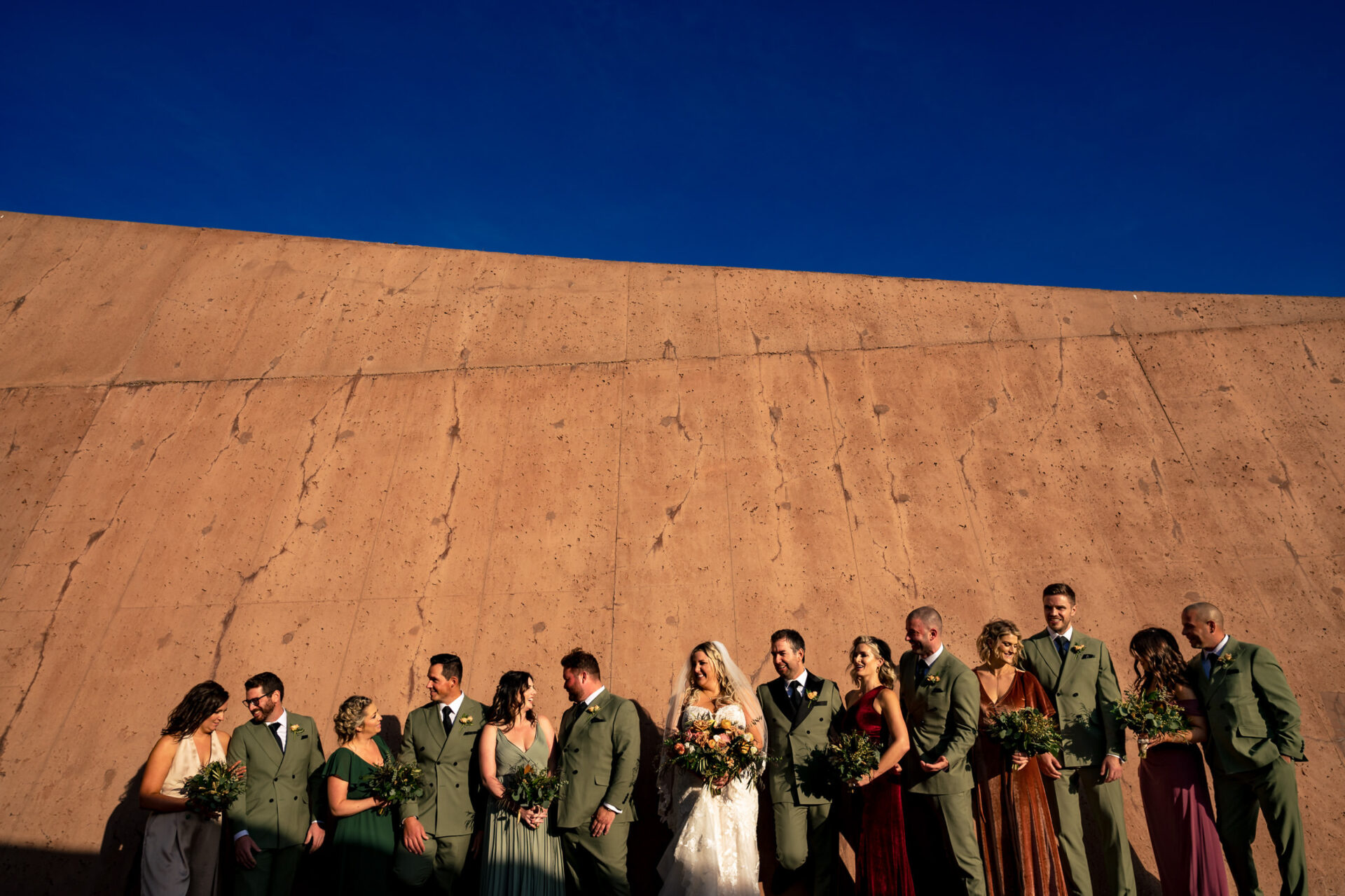 Best Winnipeg wedding photos: party in formal attire against a textured wall and clear sky.
