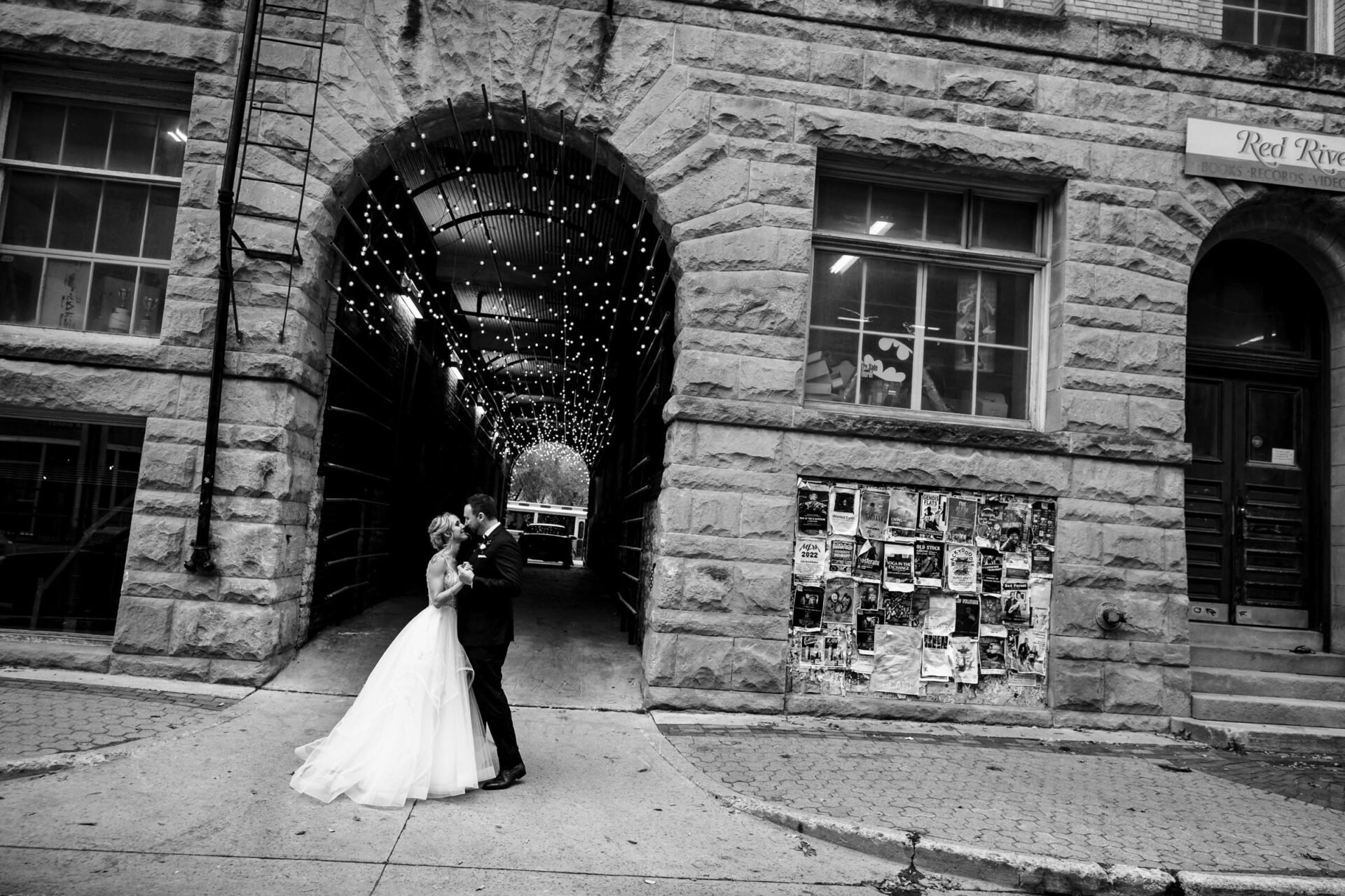Bride and groom share a kiss under lit archway, capturing the best Winnipeg wedding moment.
