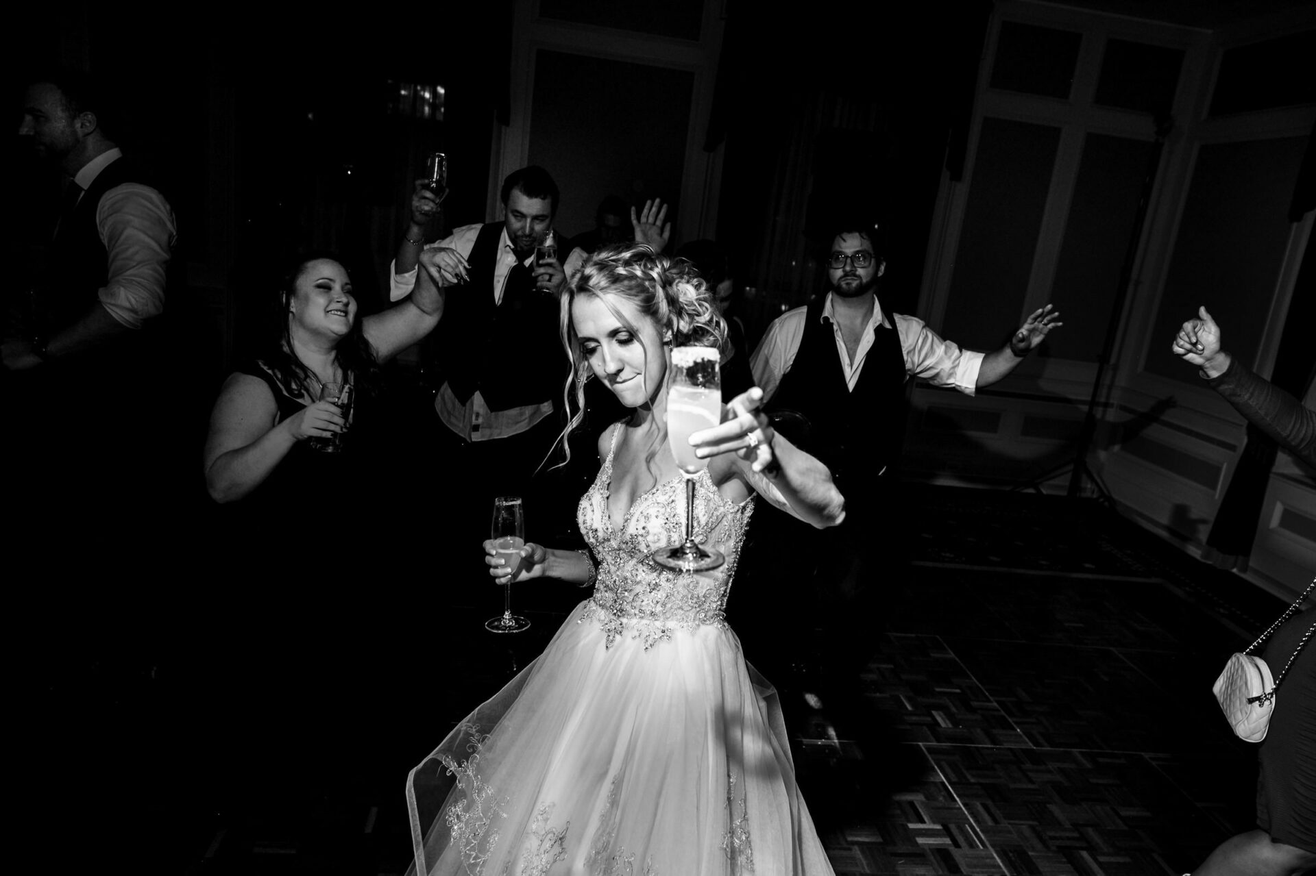 Bride dancing joyfully with friends, champagne in hand, at best Winnipeg wedding celebration.