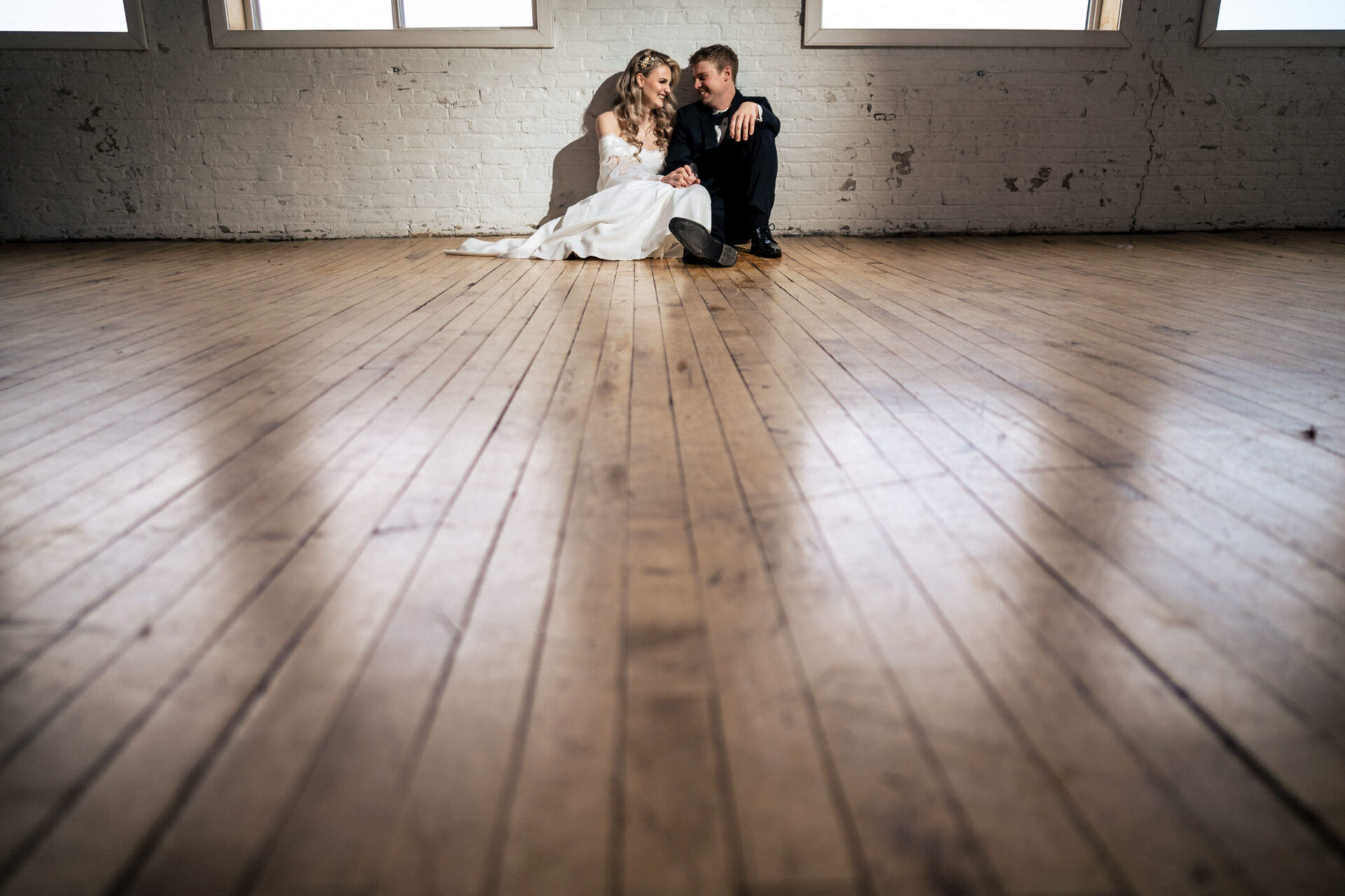 Bride and groom embrace on a wooden floor, the best Winnipeg wedding photo backdrop.