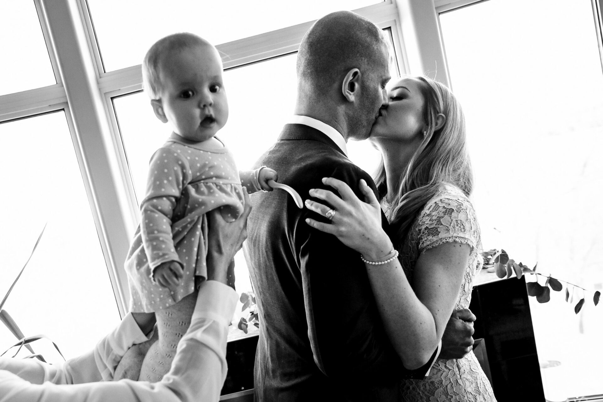 A couple shares a kiss, holding their baby in Winnipeg's best wedding photo.