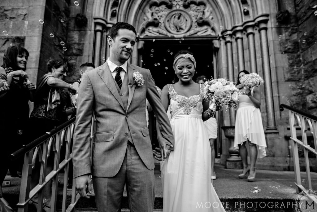 Bride and groom exit church with bubbles, celebrating their Kilkenny destination wedding.