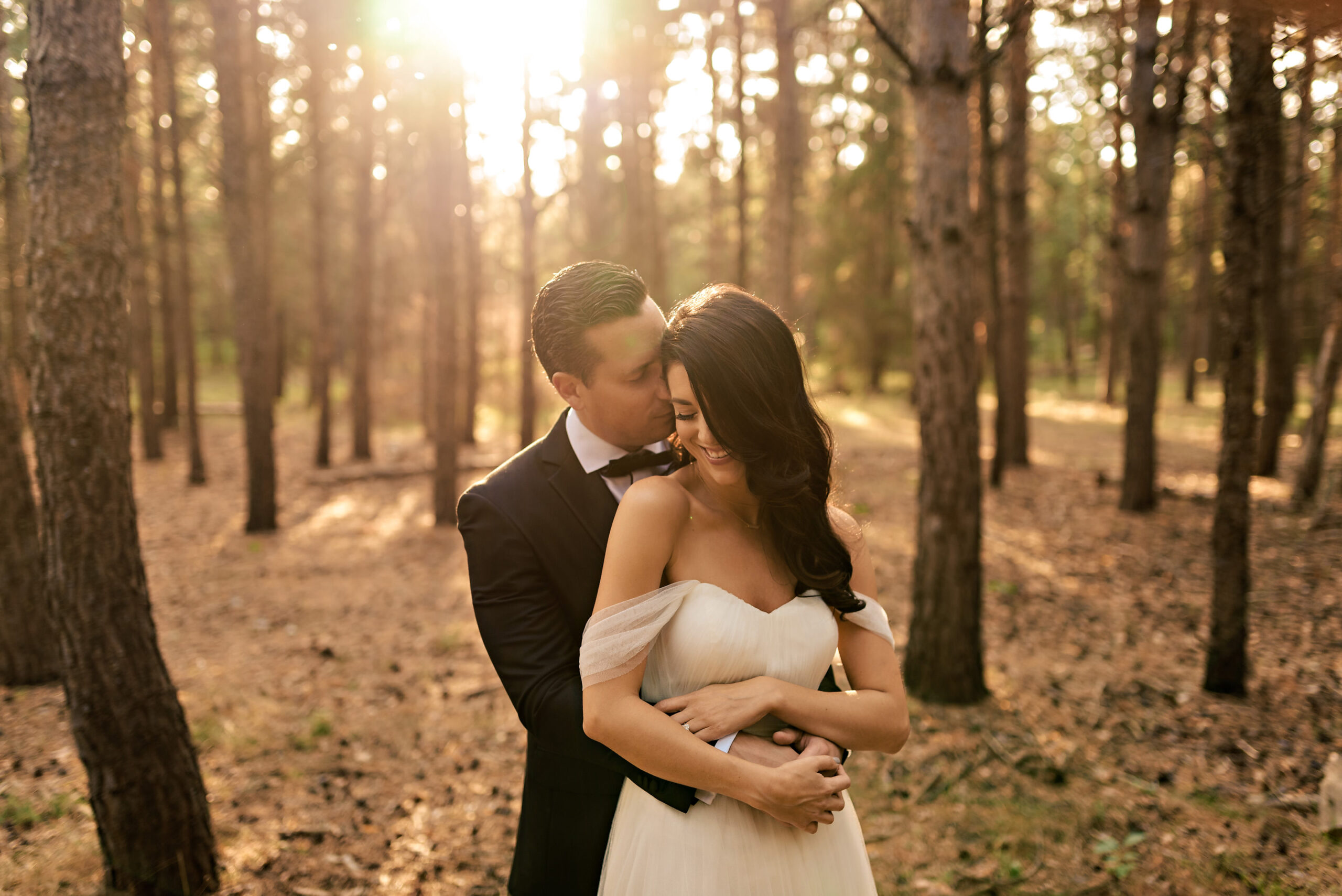 Winnipeg wedding photography captures a couple embracing in a sunlit, forested enchantment.