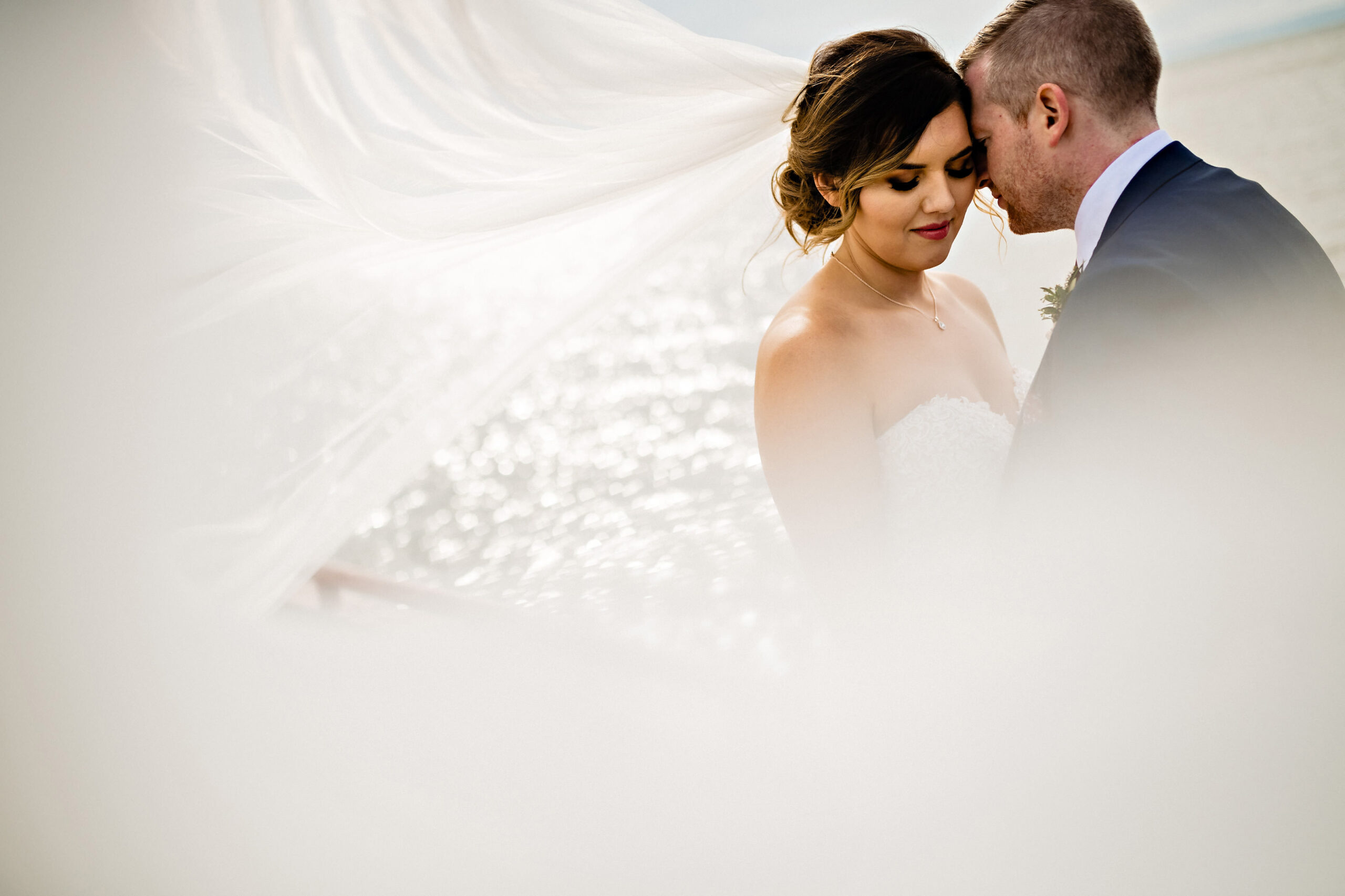 Bride and groom's intimate moment by the water, captured by Winnipeg Wedding Photography.