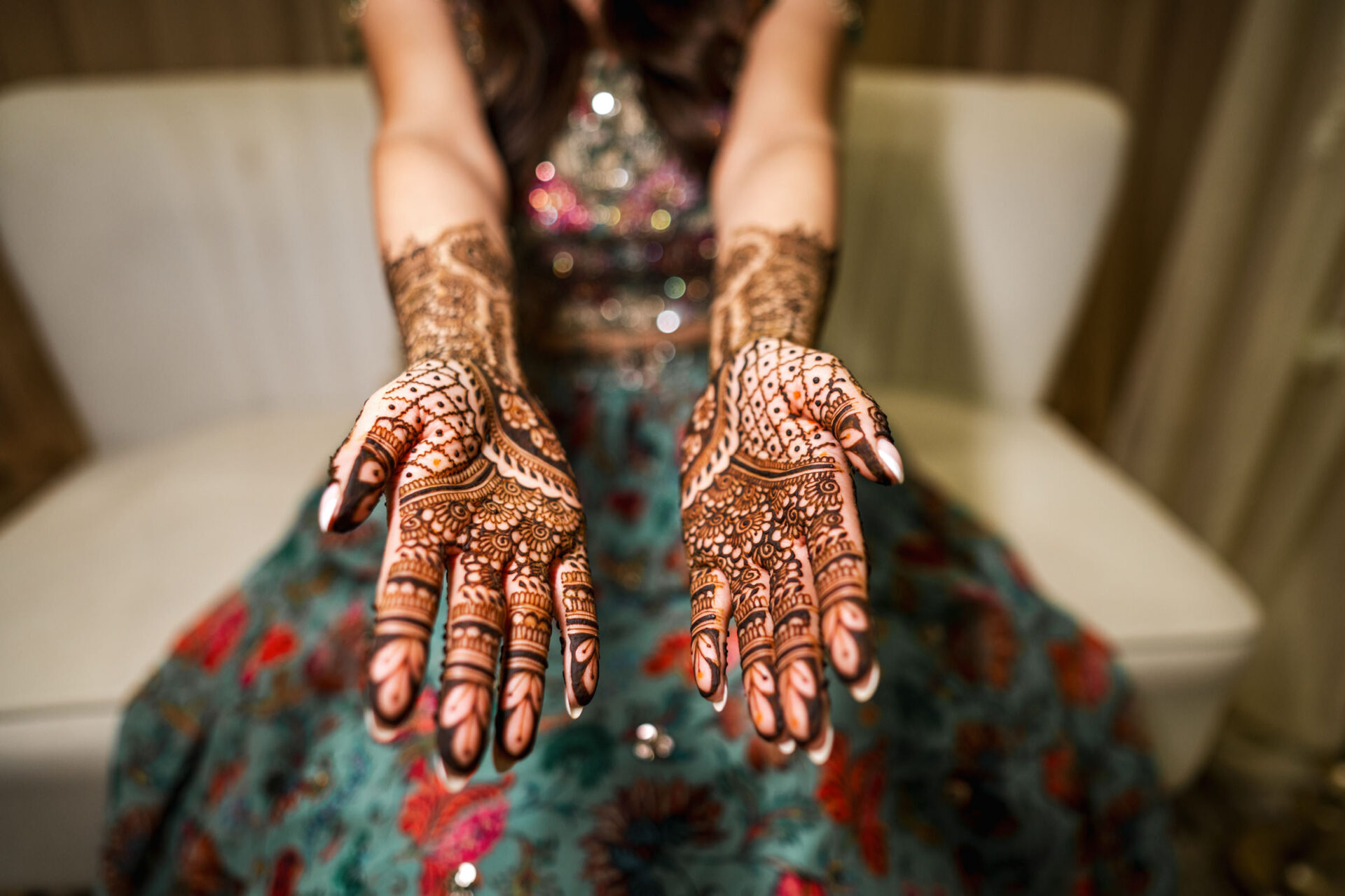 Person displaying intricate henna designs on their hands at a Sikh wedding.