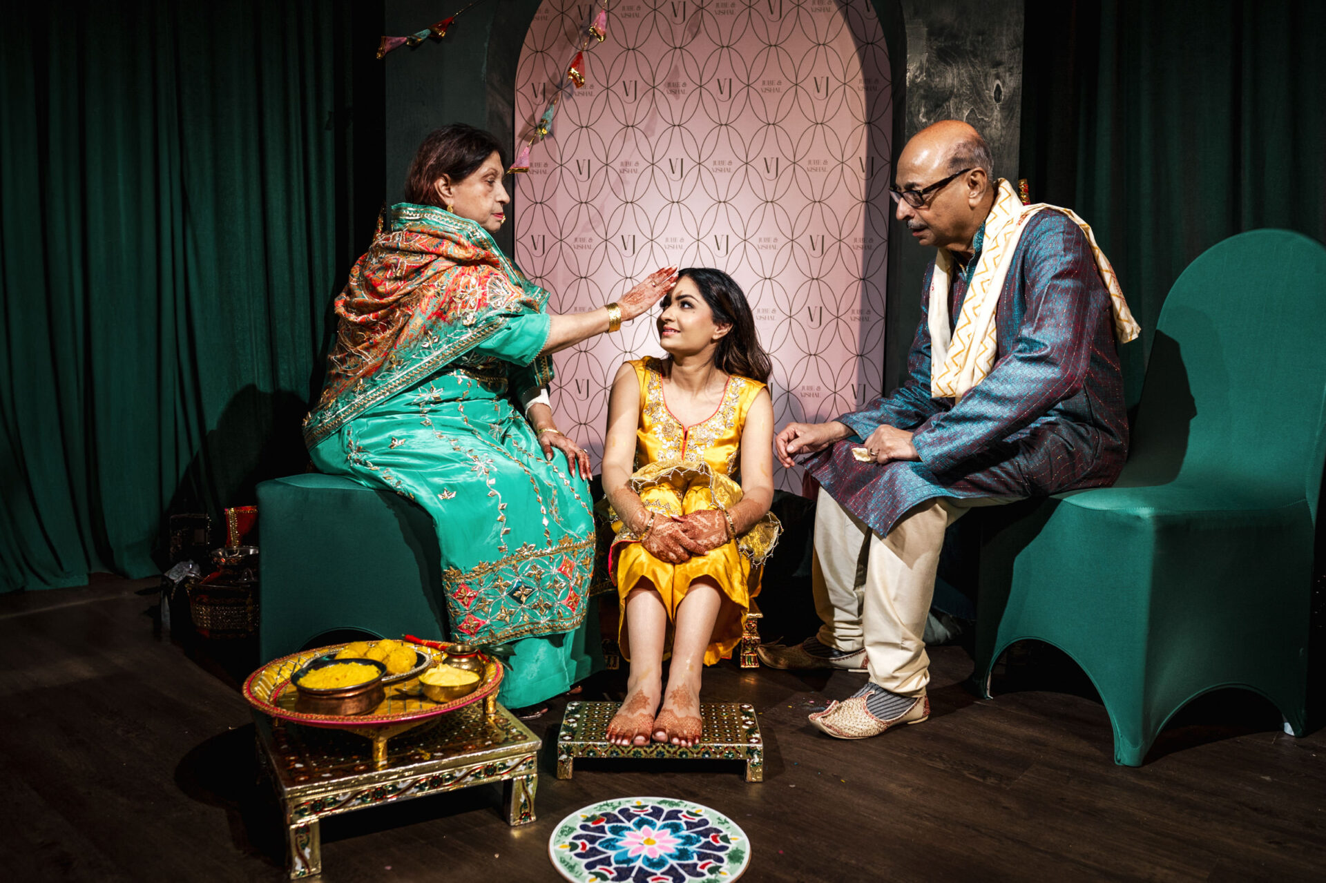 A woman in yellow sits as two elders conduct a Sikh wedding ceremony.