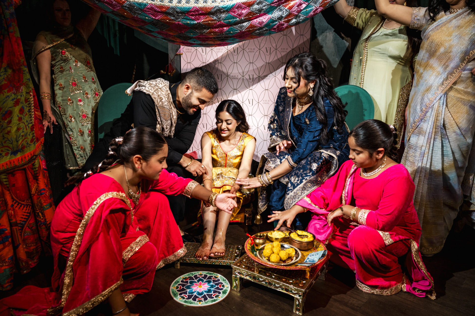 A vibrant Sikh ceremony with a woman in yellow, surrounded by colorful traditional attire.