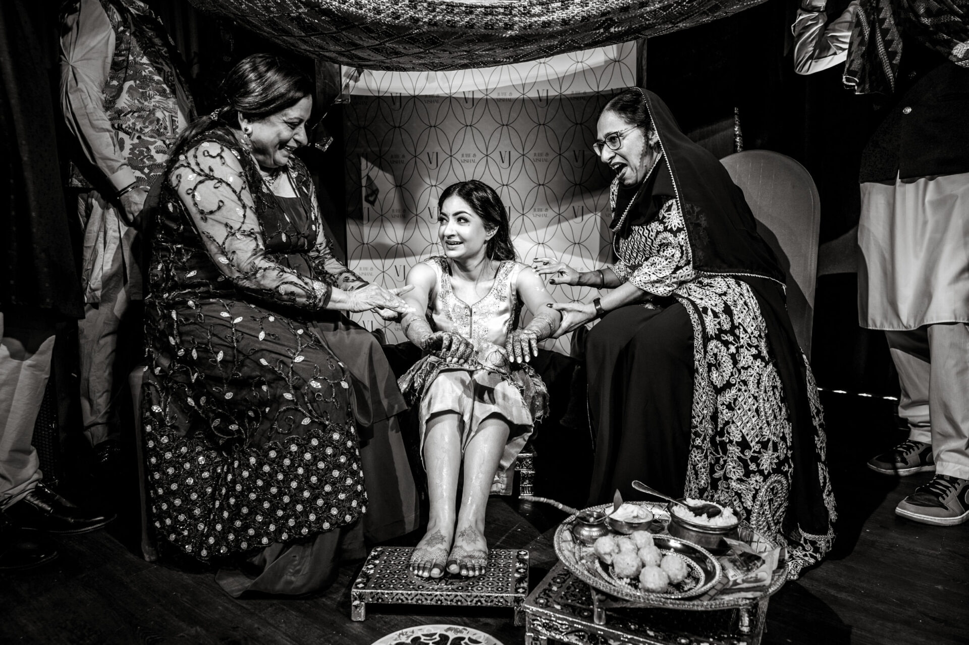 A woman at a Sikh ceremony, surrounded by two smiling women in traditional attire.